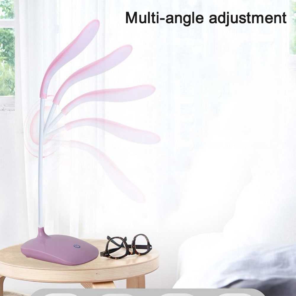 Eine Schreibtischlampe mit Multi-Winkel-Einstellung steht auf einem Holztisch. Daneben steht eine Brille. Der Hintergrund ist ein Fenster und ein weißer Vorhang.