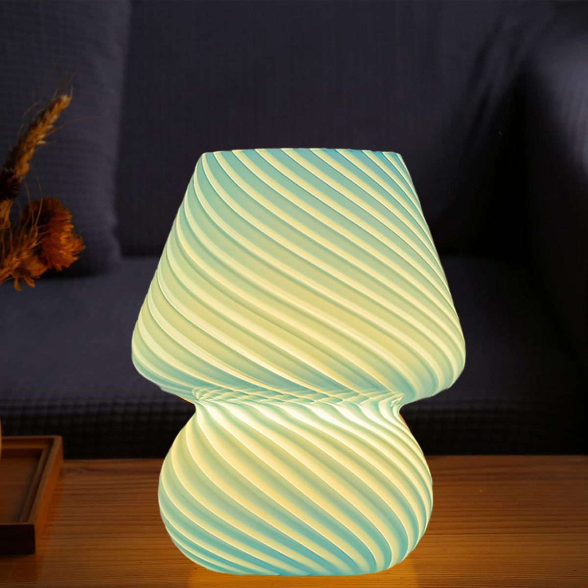 Eine pilzförmige Lampe mit Wirbelmuster in Blau- und Gelbtönen steht auf einer Holzoberfläche. Ein dunkelblauer Hintergrund.