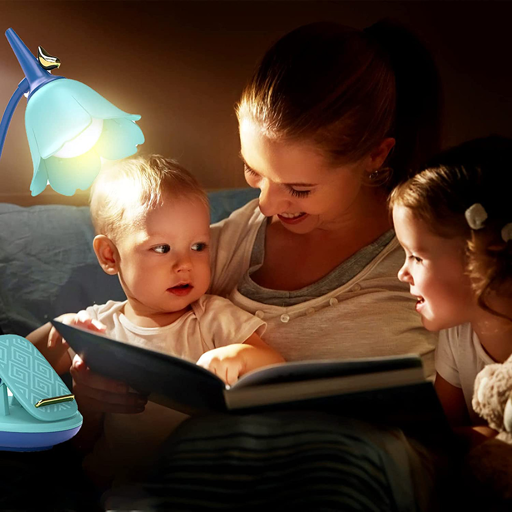 Eine Mutter liest zwei Kindern vor, beleuchtet von einer blütenförmigen Lampe. Die Kinder schauen interessiert ins Buch.