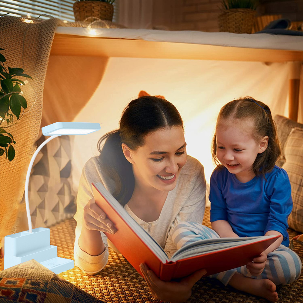 Eine Frau und ein Mädchen lesen unter einem Bett ein Buch. Links ist eine Lampe. Beide lächeln. Kissen und Decken umgeben sie.