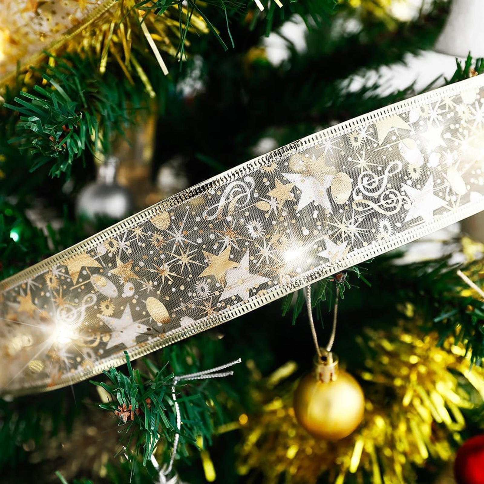 Nahaufnahme eines Weihnachtsbaums mit goldenem Band. Das Band ist mit Sternen und Noten verziert. Goldene Ornamente.