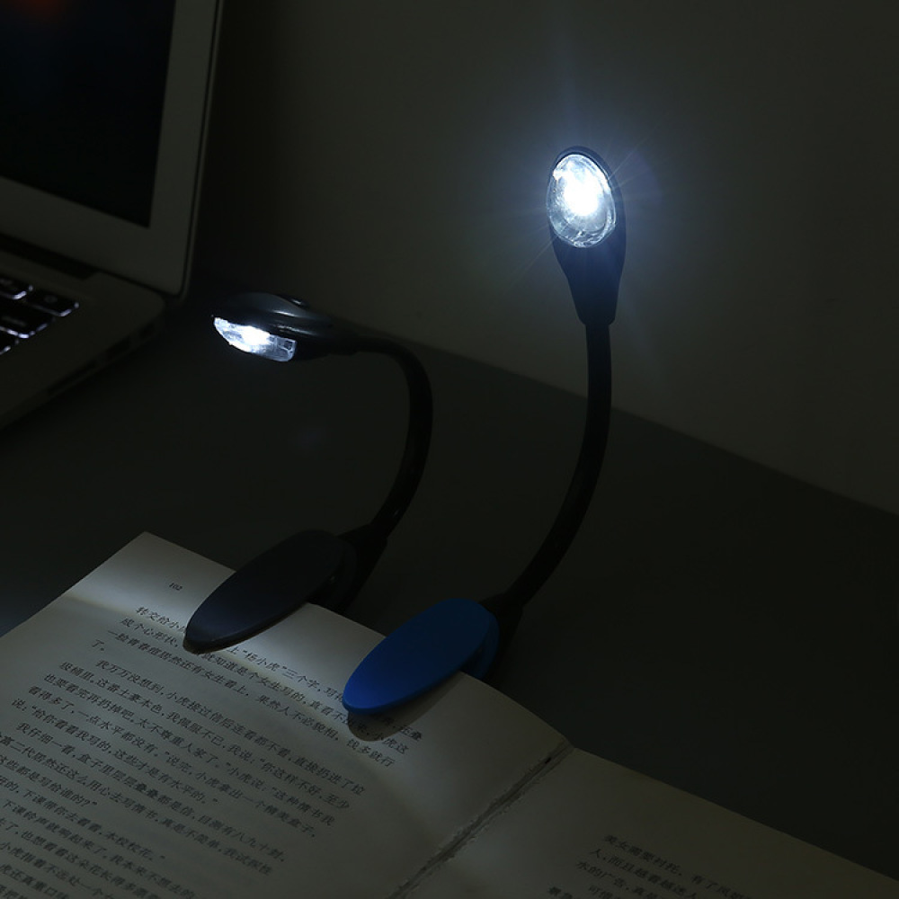 Zwei schwarze LED-Buchleuchten beleuchten ein offenes Buch. Eine Leuchte hat einen blauen Clip.
