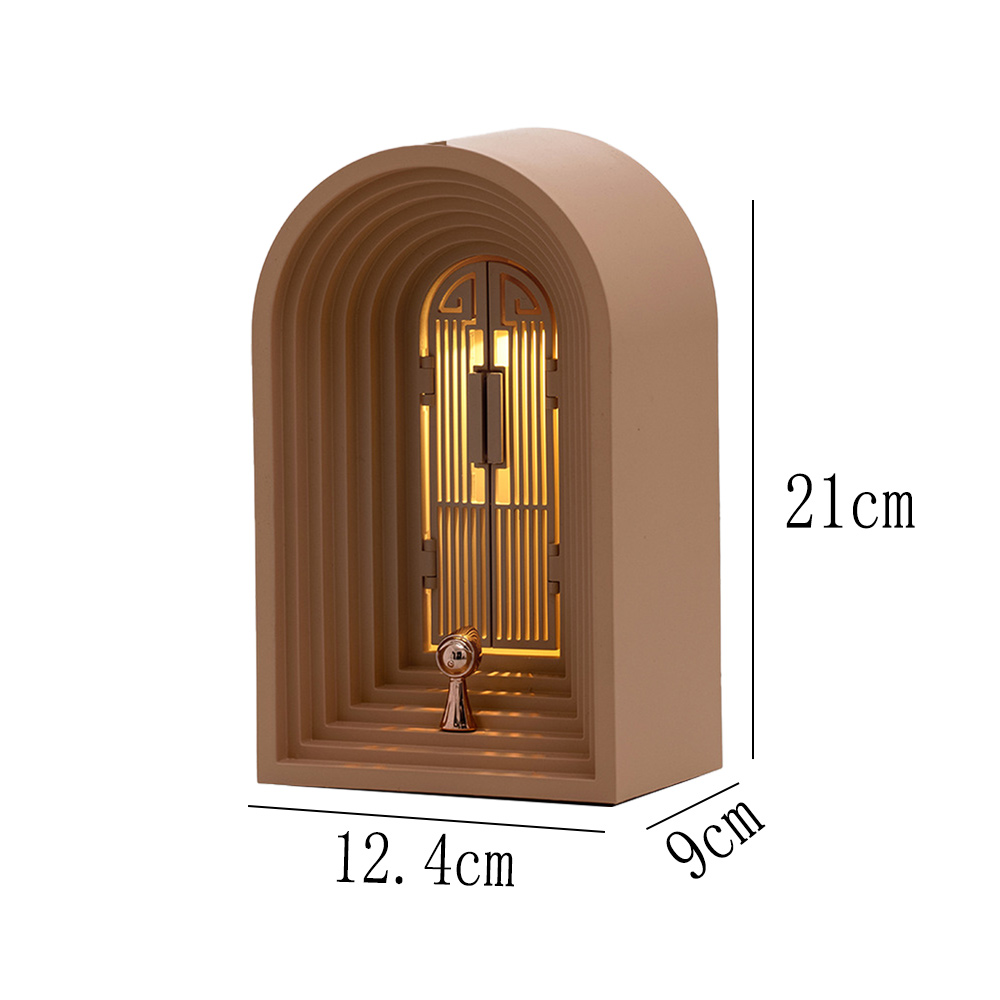 Beigefarbene bogenförmige Lampe mit goldenem Türdesign. Maße: 21 cm Höhe, 12,4 cm Breite und 9 cm Tiefe. Licht scheint darin.