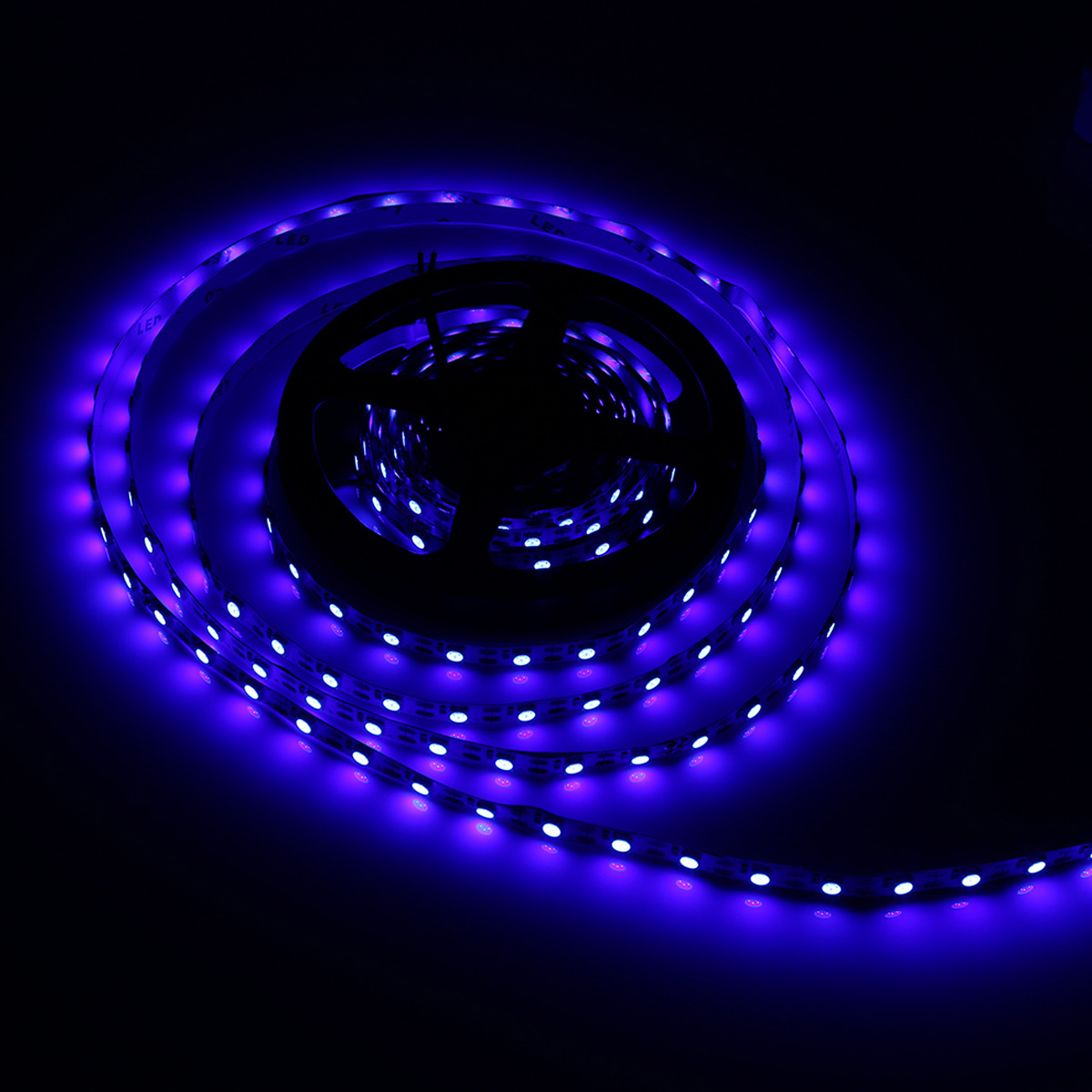 Eine aufgerollte LED-Leiste mit violetten Lichtern vor schwarzem Hintergrund. Die Lichter sind hell und erzeugen einen Leuchteffekt.