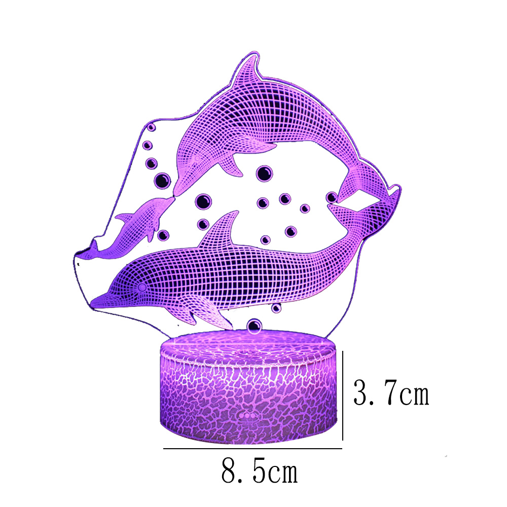Eine lila Delfinlampe mit drei Delfinen, einigen Blasen und einem runden Sockel. Maße sind 8,5 cm x 3,7 cm.