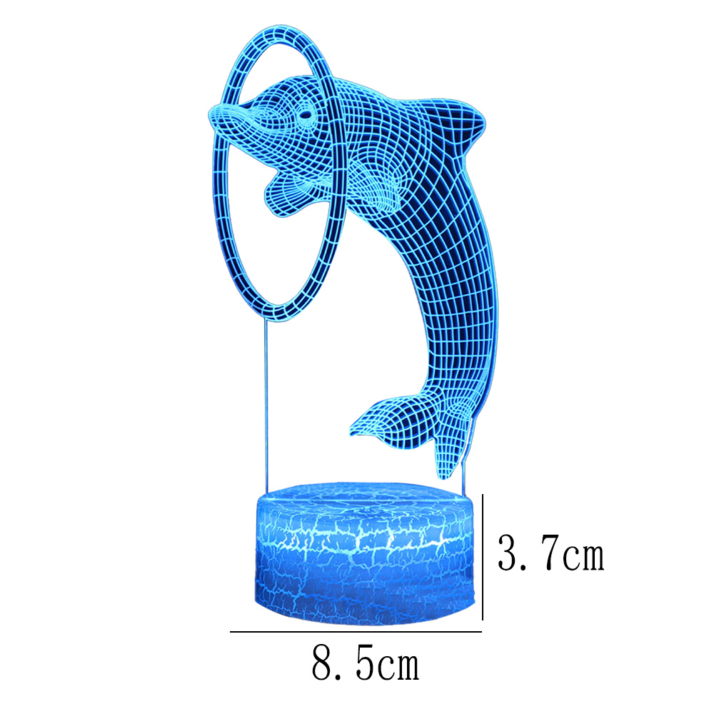 Eine blaue Delfinfigur, die durch einen Reifen springt. Der Delfin steht auf einem blauen Sockel. Maße sind enthalten. Weißer Hintergrund.