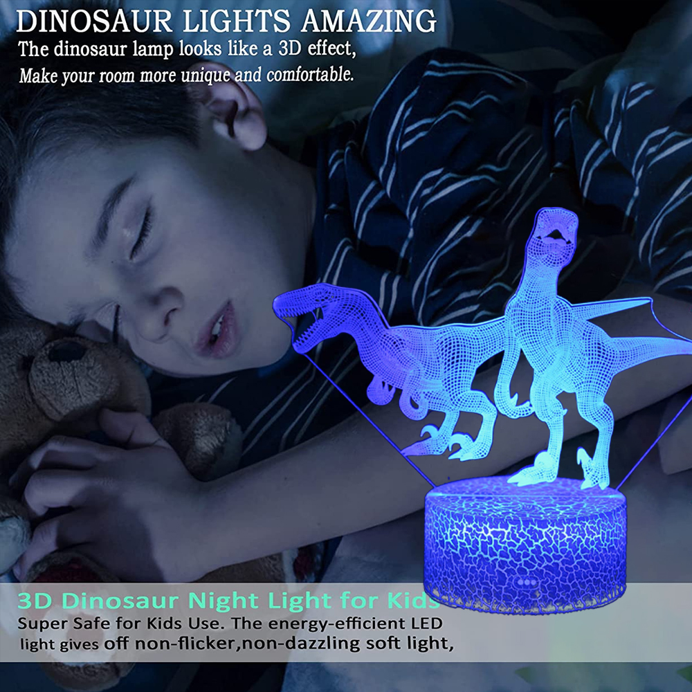 Ein Kind schläft, ein dinosaurierförmiges Nachtlicht leuchtet. Das Licht ist blau und erzeugt einen 3D-Effekt. Das Kind hält einen Teddybären.