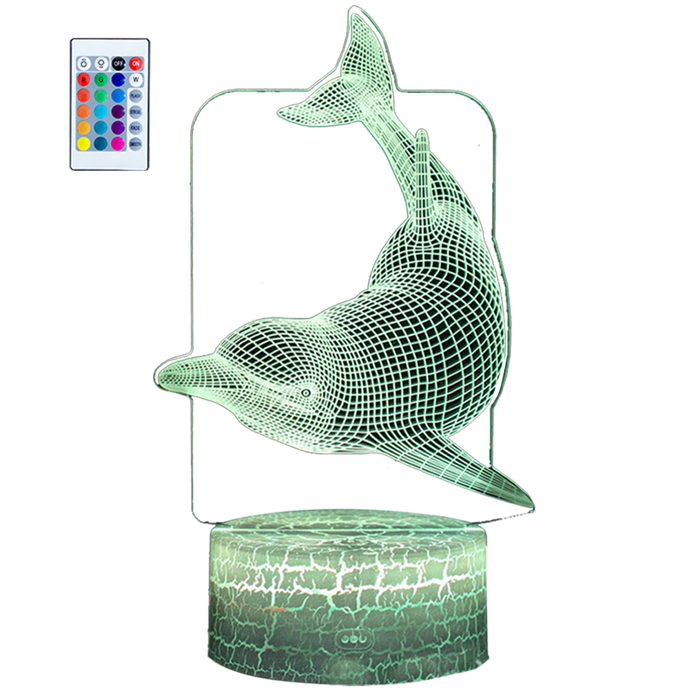 Eine 3D-Delfinlampe mit Fernbedienung. Der Delfin ist grün umrandet, mit einem grünen, rissigen Sockel. Links ist eine Fernbedienung.