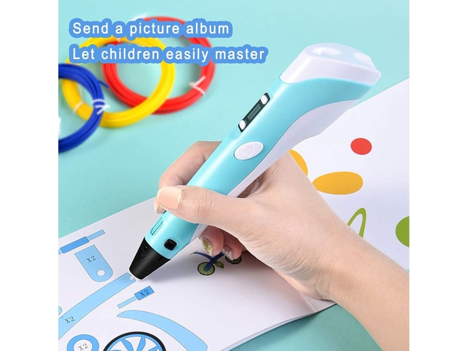 Eine Hand hält einen blauen 3D-Stift und zeichnet auf Papier. Farbige Filamente und der Text 'Sende ein Fotoalbum' sind im Hintergrund.