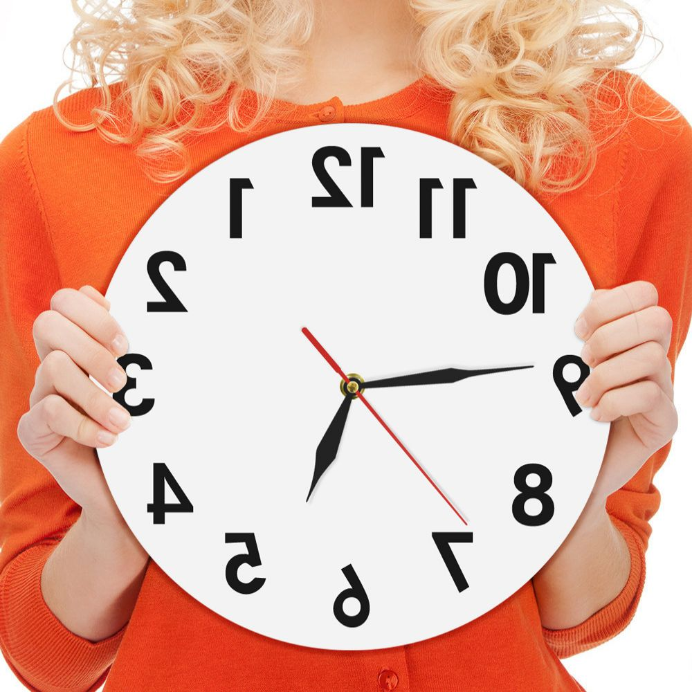 Frau in Orange hält eine weiße Uhr, Zeiger auf 7:10. Blondes Haar, orangefarbener Pullover. Uhr hat schwarze Zahlen und Zeiger, roter Sekundenzeiger.