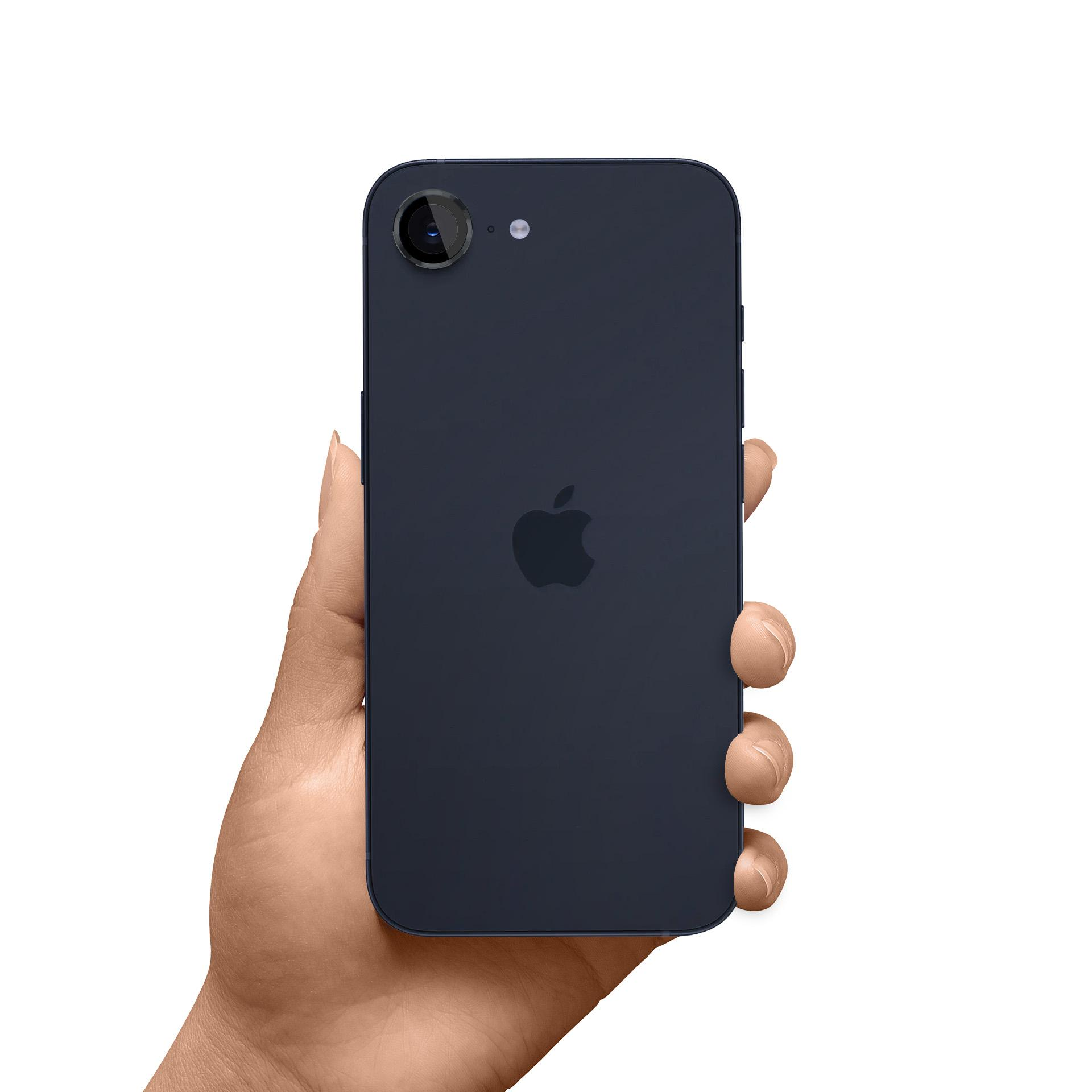 Dłoń trzymająca ciemnoniebieskiego iPhone'a. Widoczne logo Apple. Aparat telefonu jest u góry.