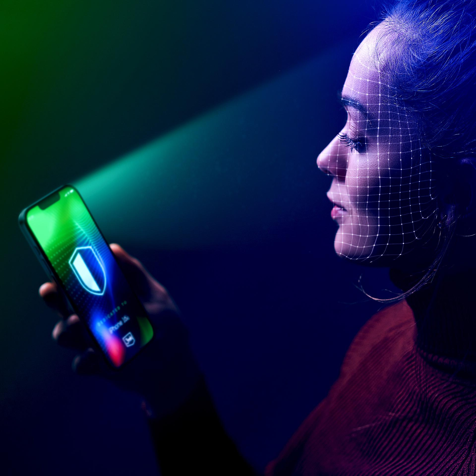 Una donna usa Face ID sul suo telefono. Una griglia sovrappone il suo viso. Lo schermo mostra un'icona a scudo.