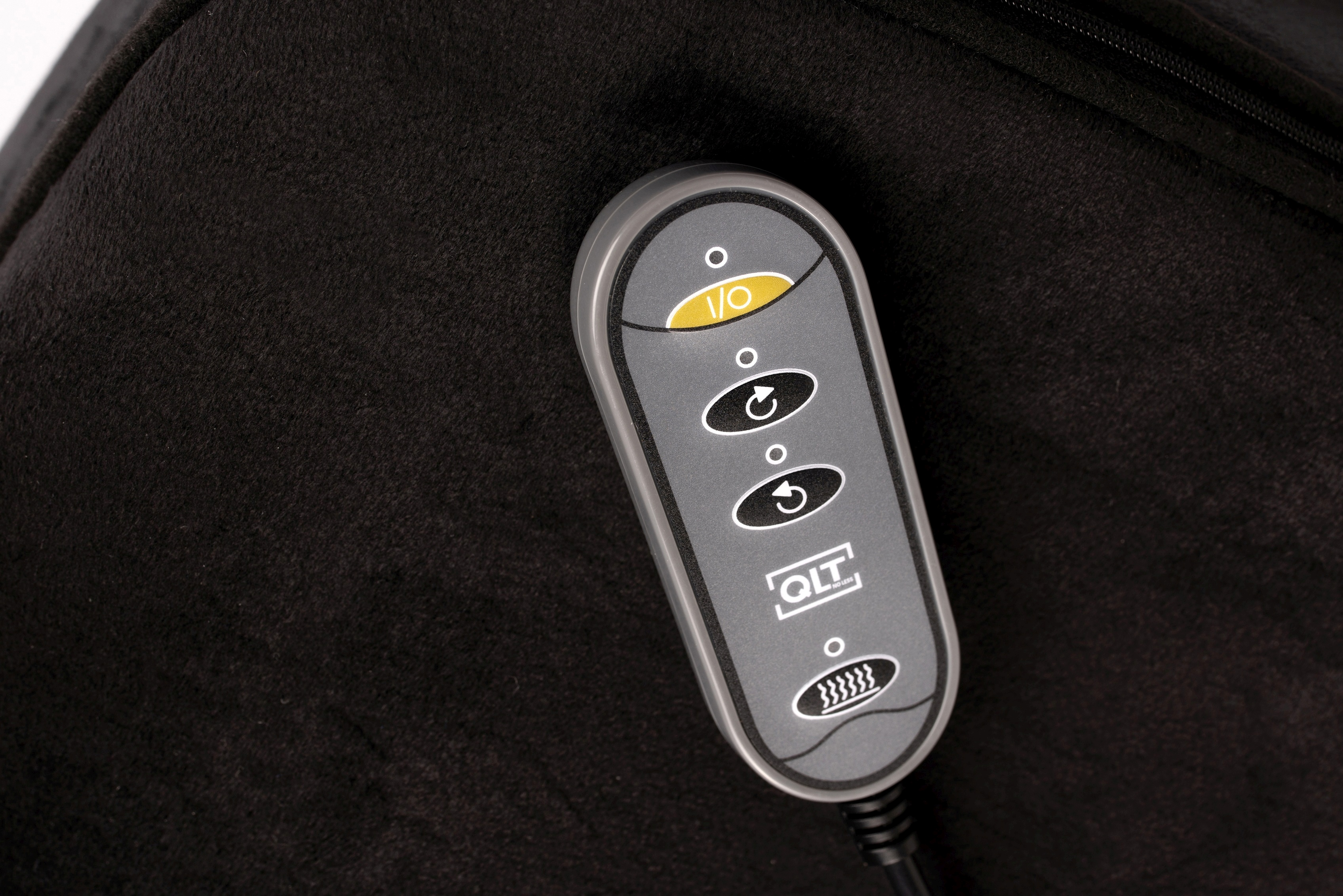 A gray control panel with buttons for power, direction, and heat sits on a black fabric background.