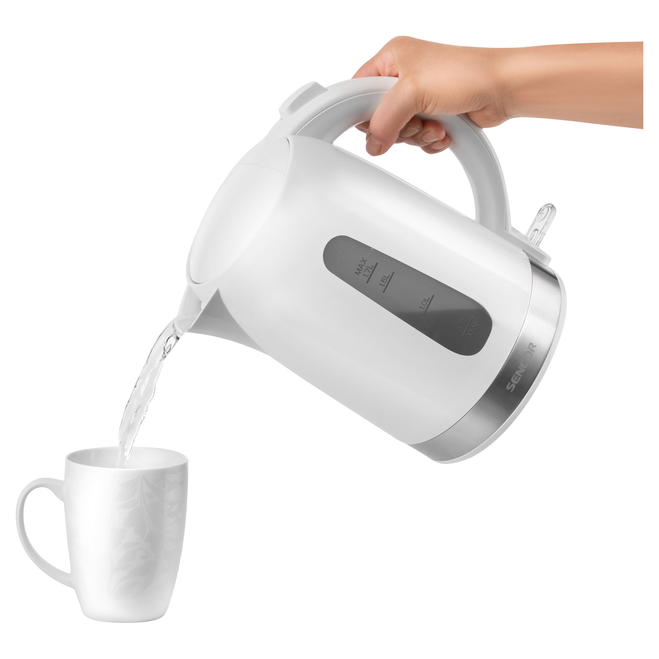 Una mano versa acqua da un bollitore elettrico bianco in una tazza bianca con motivi floreali, su sfondo bianco.