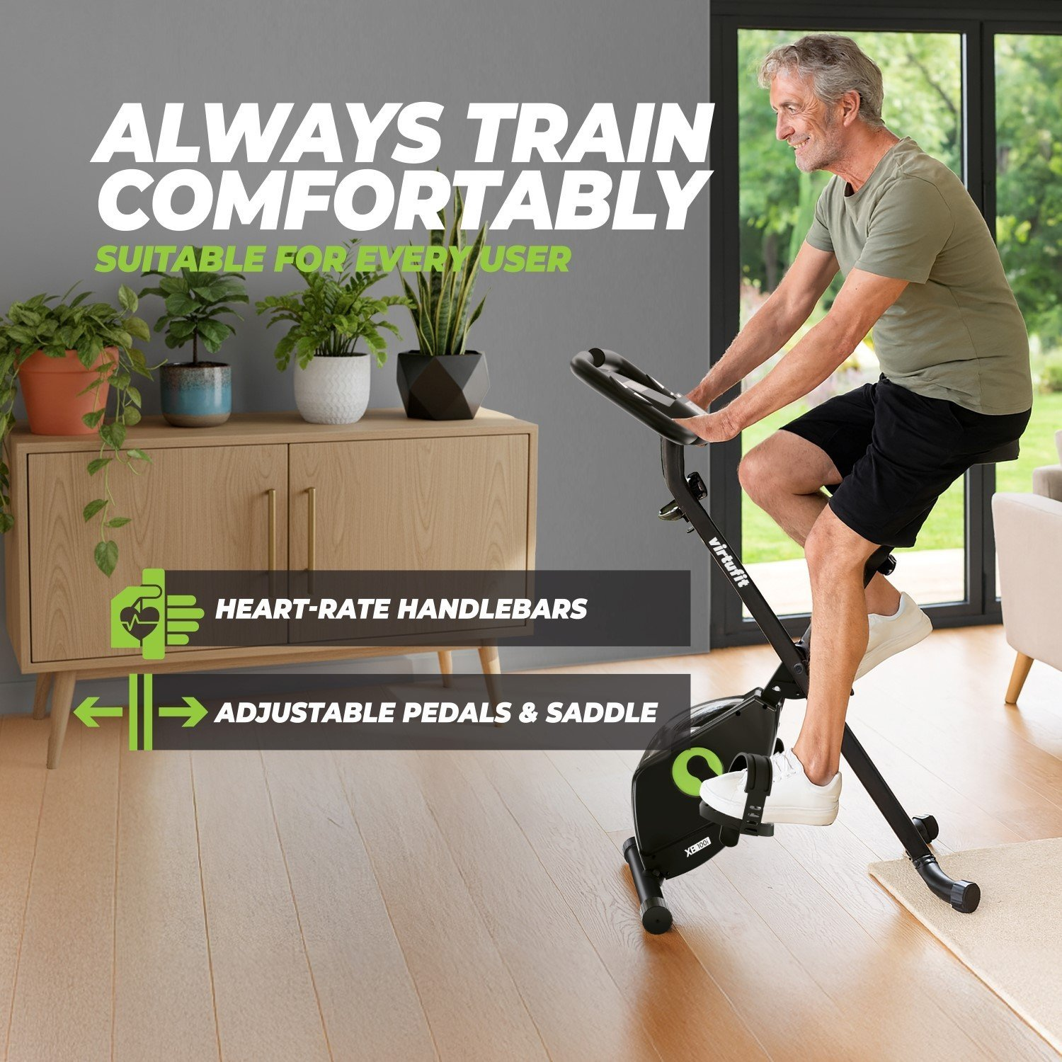Ein älterer Mann trainiert auf einem Heimtrainer. Das Fahrrad ist schwarz mit grünen Akzenten. Pflanzen und Möbel befinden sich im Hintergrund.