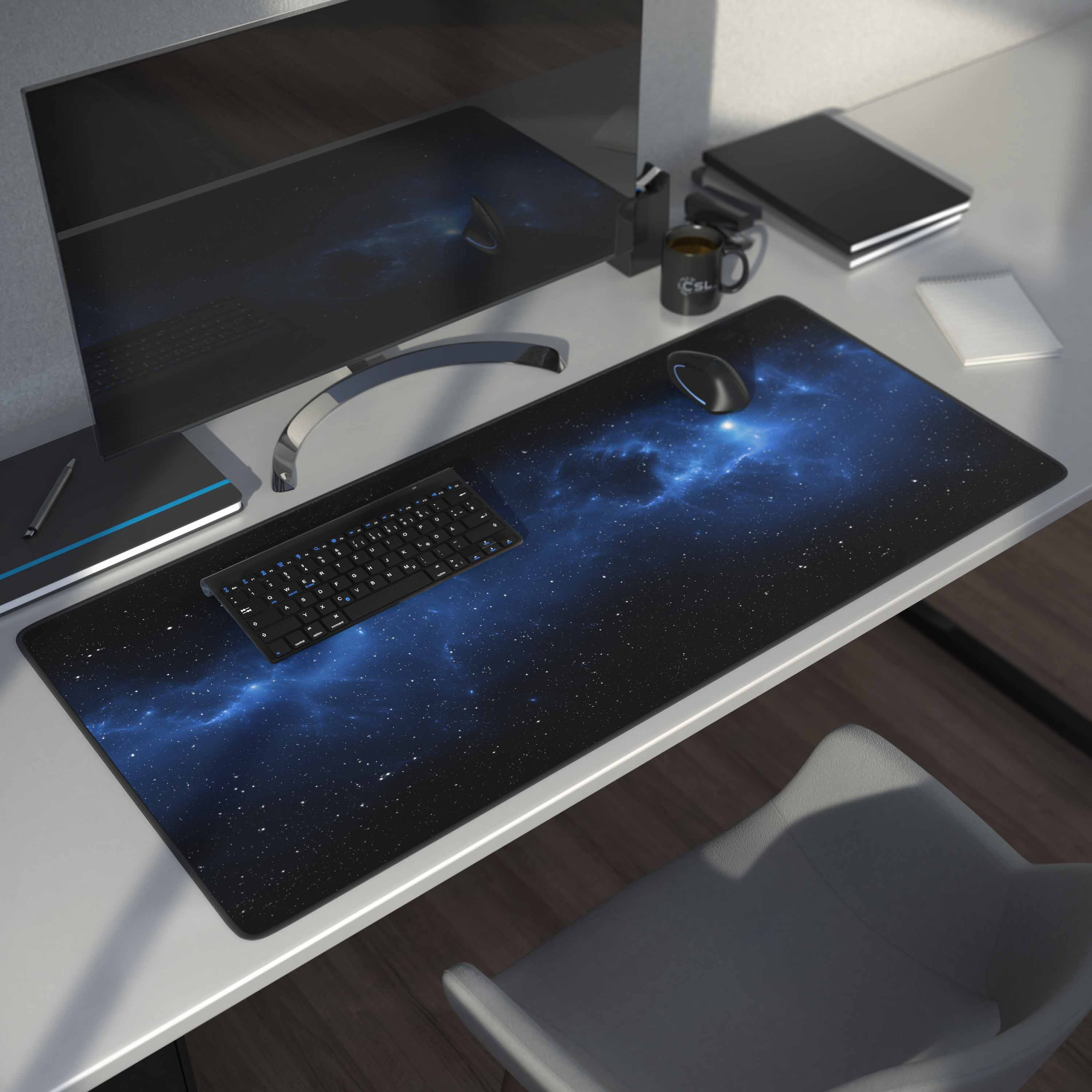 Schreibtisch mit Monitor, Tastatur, Maus und Weltraum-Mauspad. Eine Tasse und ein Notizblock sind ebenfalls sichtbar.