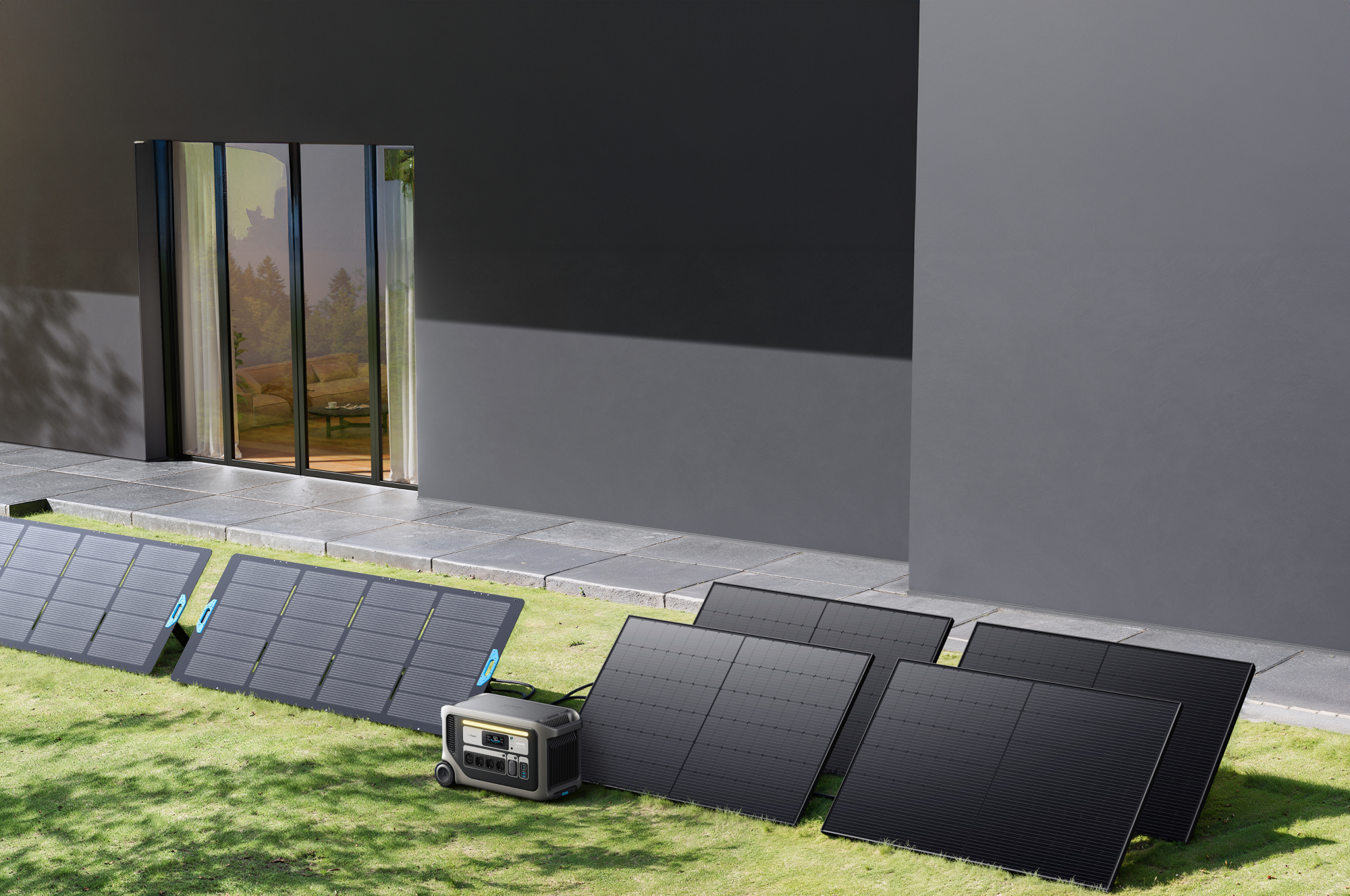 Panele słoneczne na trawie obok domu. Stacja zasilania również znajduje się na trawie. Okno odbija otoczenie.