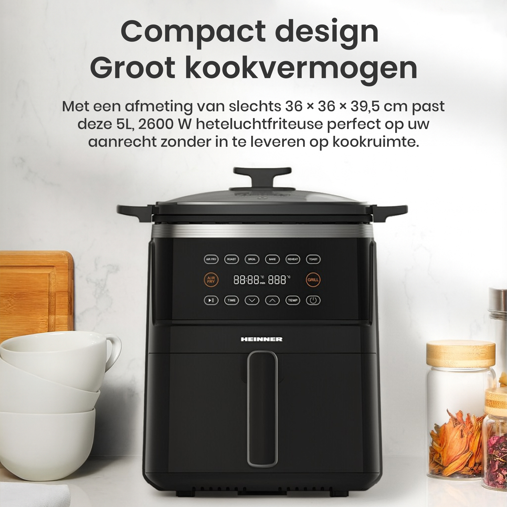 Black air fryer on a white countertop. It has a digital display and buttons. Beside it are white bowls and glass jars.