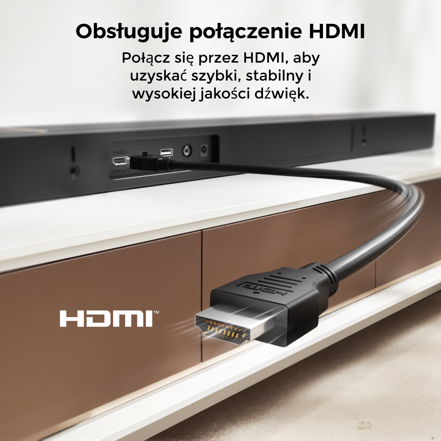 Czarny kabel HDMI jest podłączony do soundbaru na białej i brązowej szafce. Widoczne jest logo HDMI.