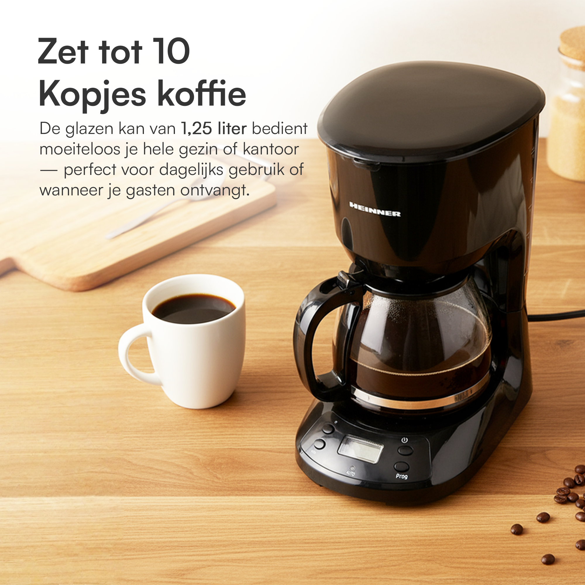 Eine schwarze Kaffeemaschine mit Glaskaraffe, eine weiße Tasse mit Kaffee und Kaffeebohnen auf Holz.