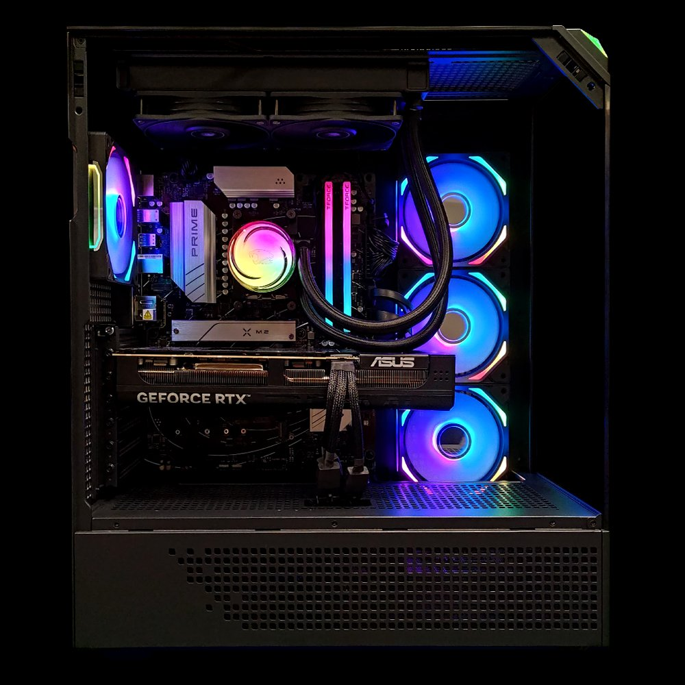 Interior de una caja de PC con componentes iluminados con RGB. Tarjeta gráfica, RAM, refrigerador de CPU y ventiladores visibles, con luces.