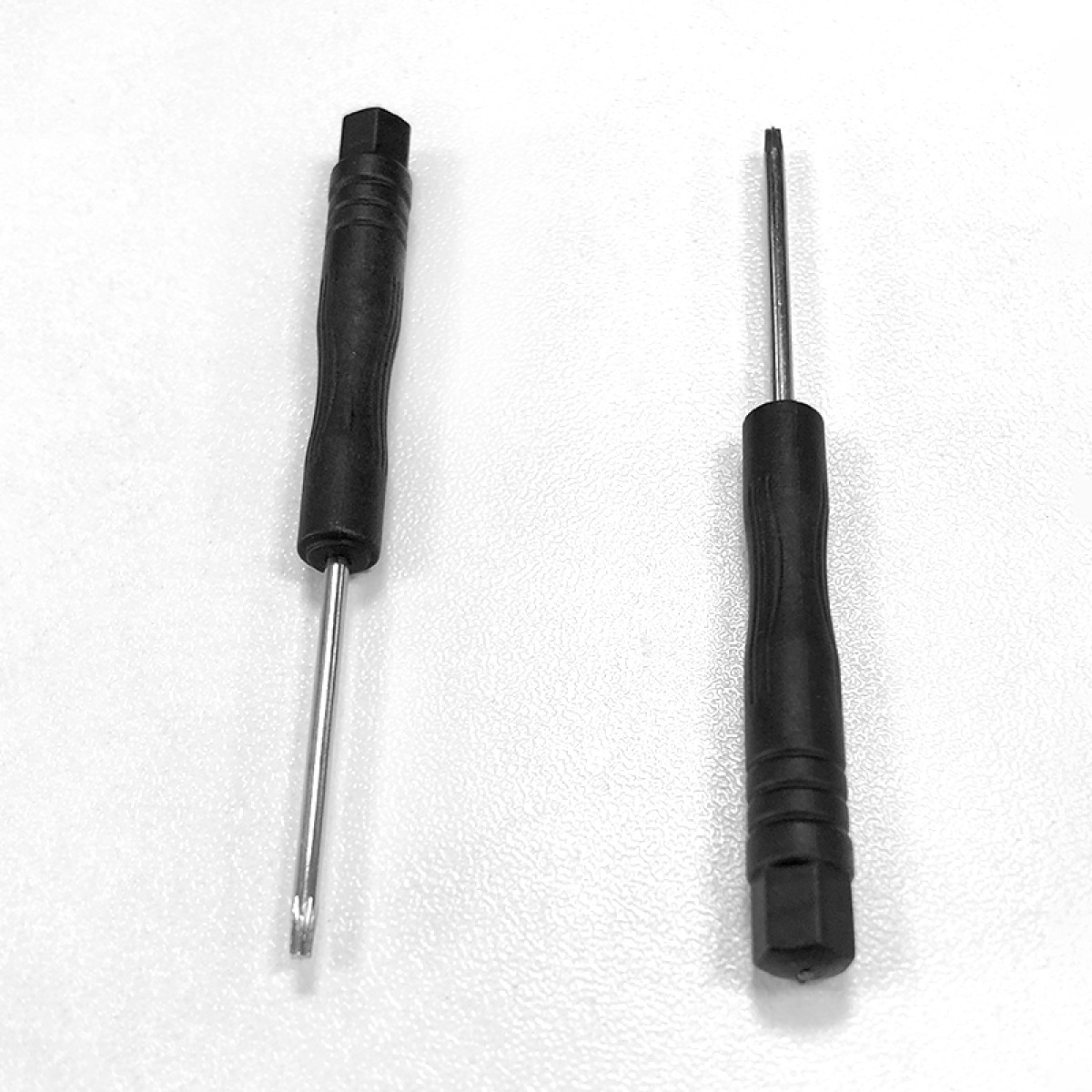 Dwa czarne śrubokręty na białej powierzchni. Jeden ma główkę w kształcie gwiazdy, drugi płaską główkę.