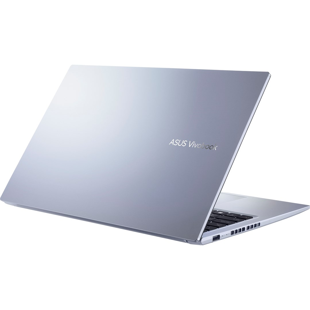 Srebrny laptop ASUS Vivobook jest lekko otwarty, widoczna klawiatura. Tło jest białe.