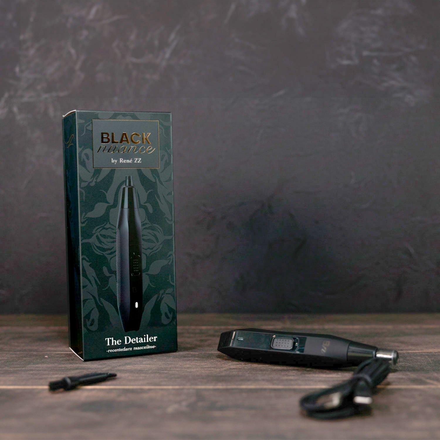 Un dispositivo de aseo negro y su caja sobre una superficie de madera. La caja dice 'BLACK nuance'. Se ve un cable de carga.