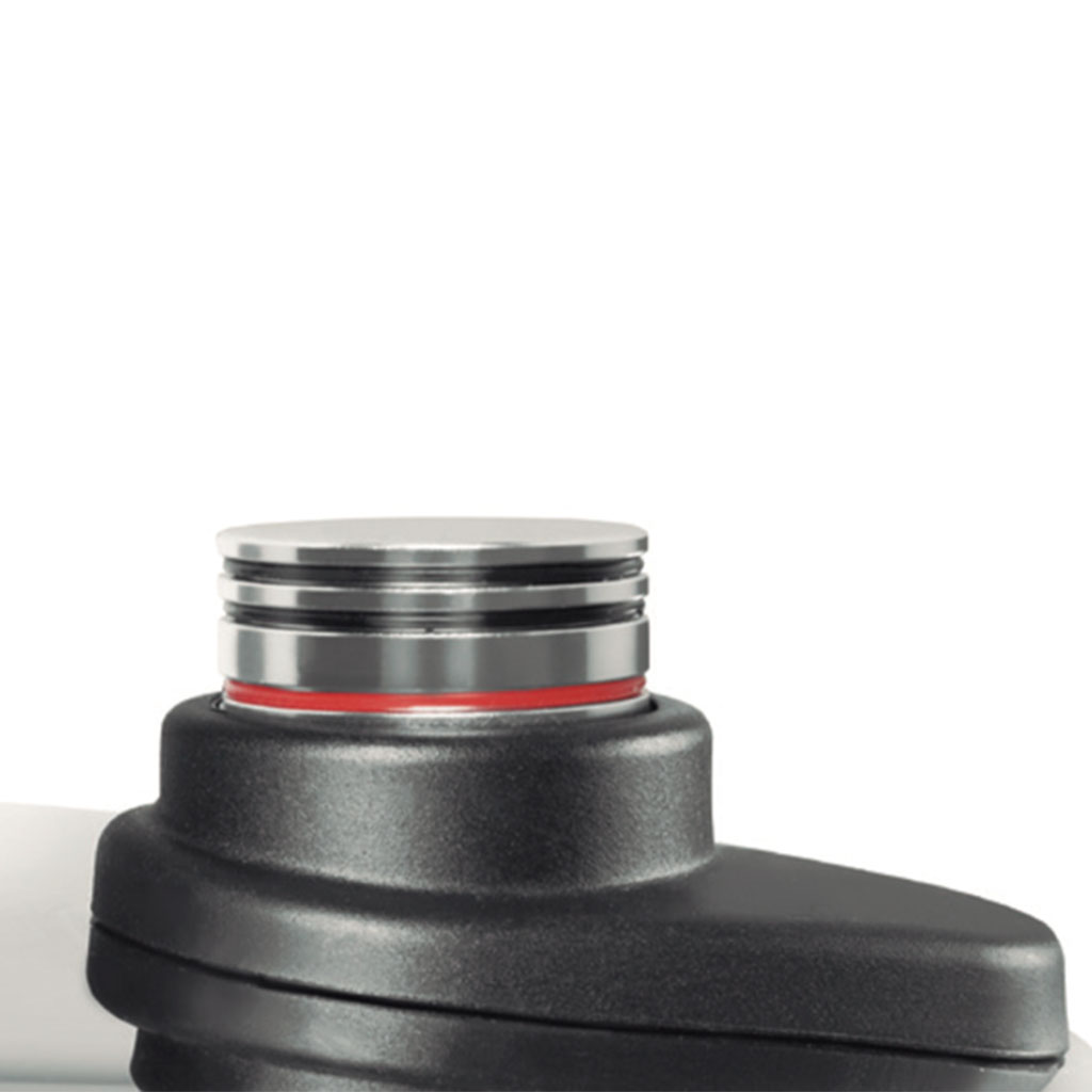 Primer plano de un dispositivo negro con una parte superior plateada. Un anillo rojo se encuentra entre las partes plateadas y negras. Fondo blanco.