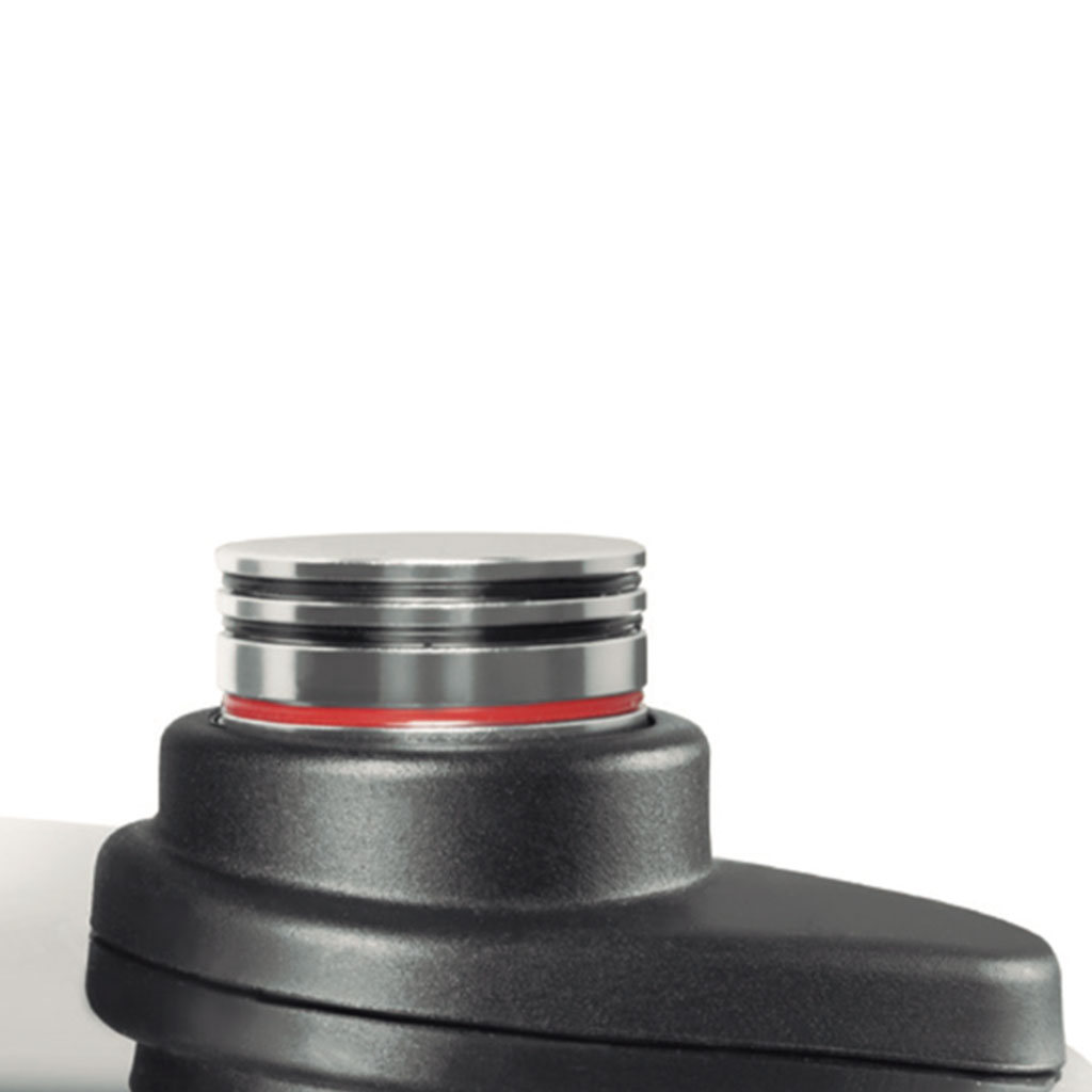 Primer plano de un dispositivo negro con parte superior plateada. Se ve un anillo rojo. El fondo es blanco, con vista parcial.