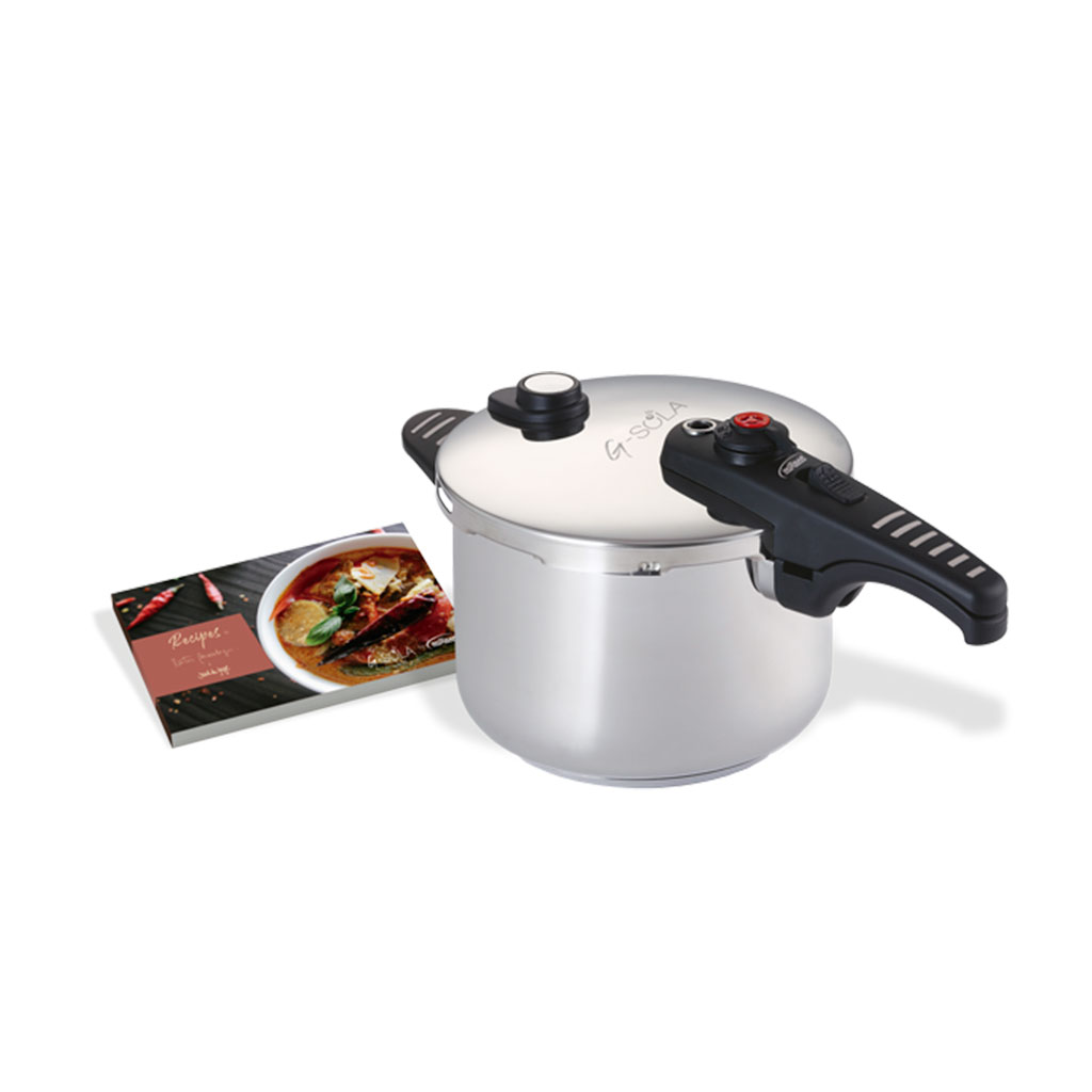 Una olla a presión de acero inoxidable con asa negra y un libro de recetas. El libro muestra una imagen de comida.