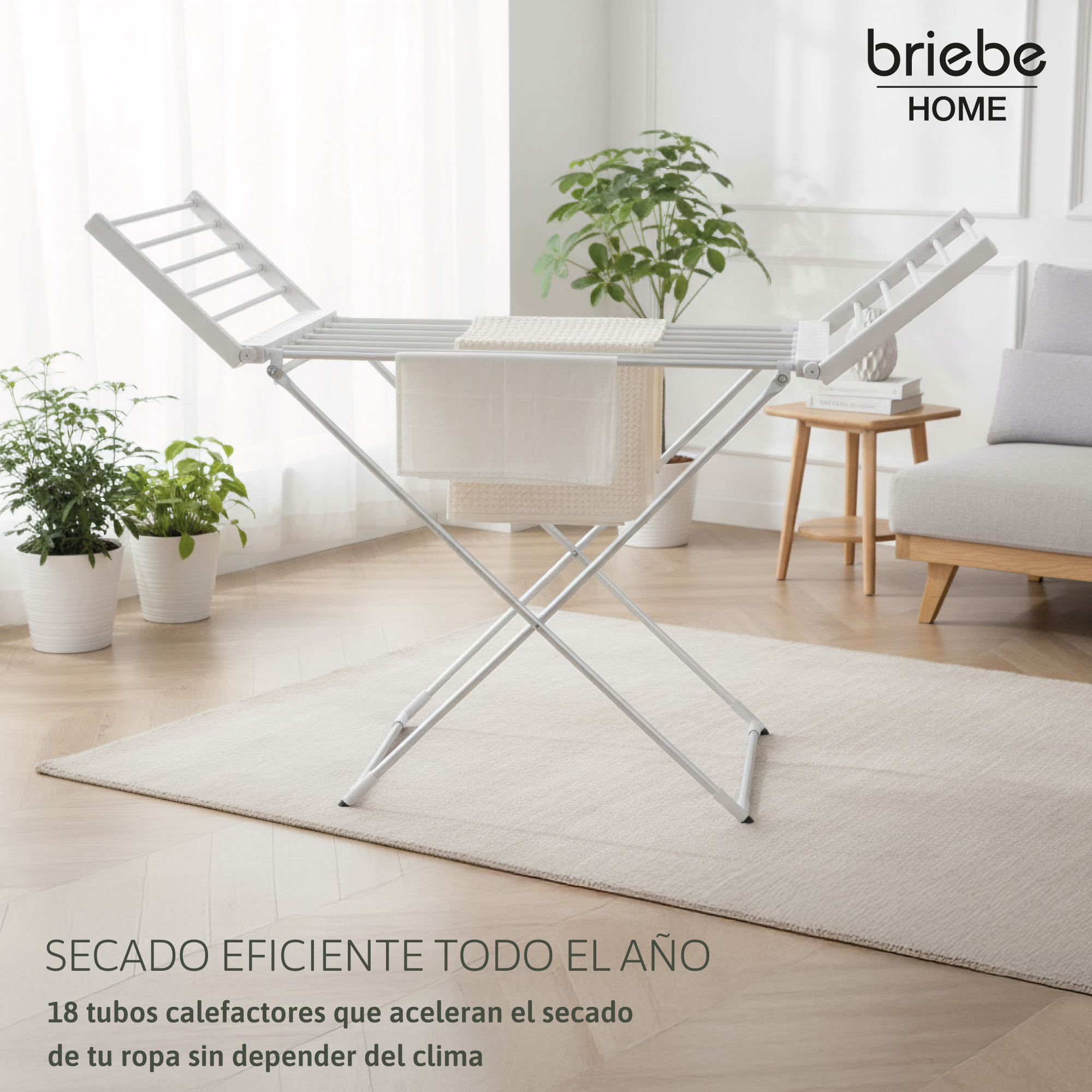 Tendedero blanco con toallas en una sala de estar. También hay plantas y un sofá.