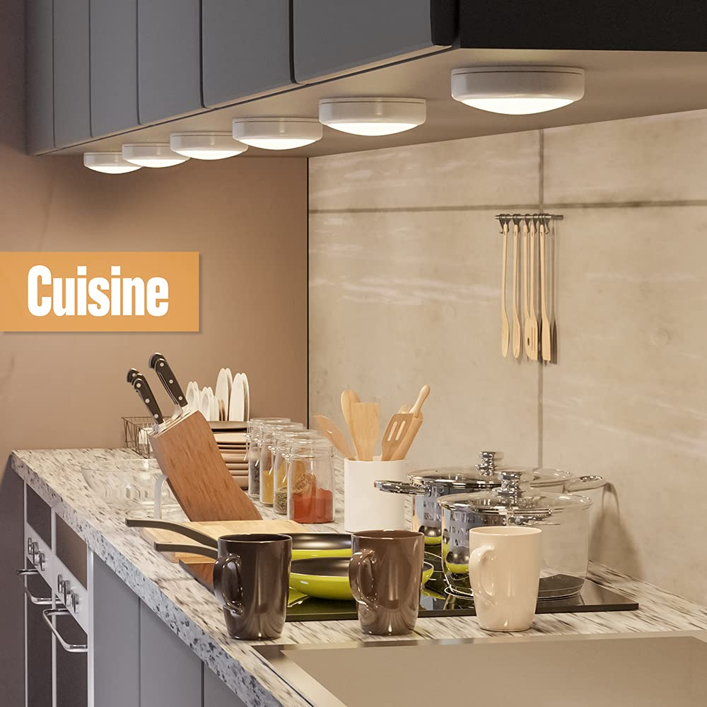 Eine Küchenszene mit Messern, Tassen, Pfannen und Utensilien. Deckenleuchten beleuchten die Arbeitsplatte. Das Wort "Cuisine" wird angezeigt.