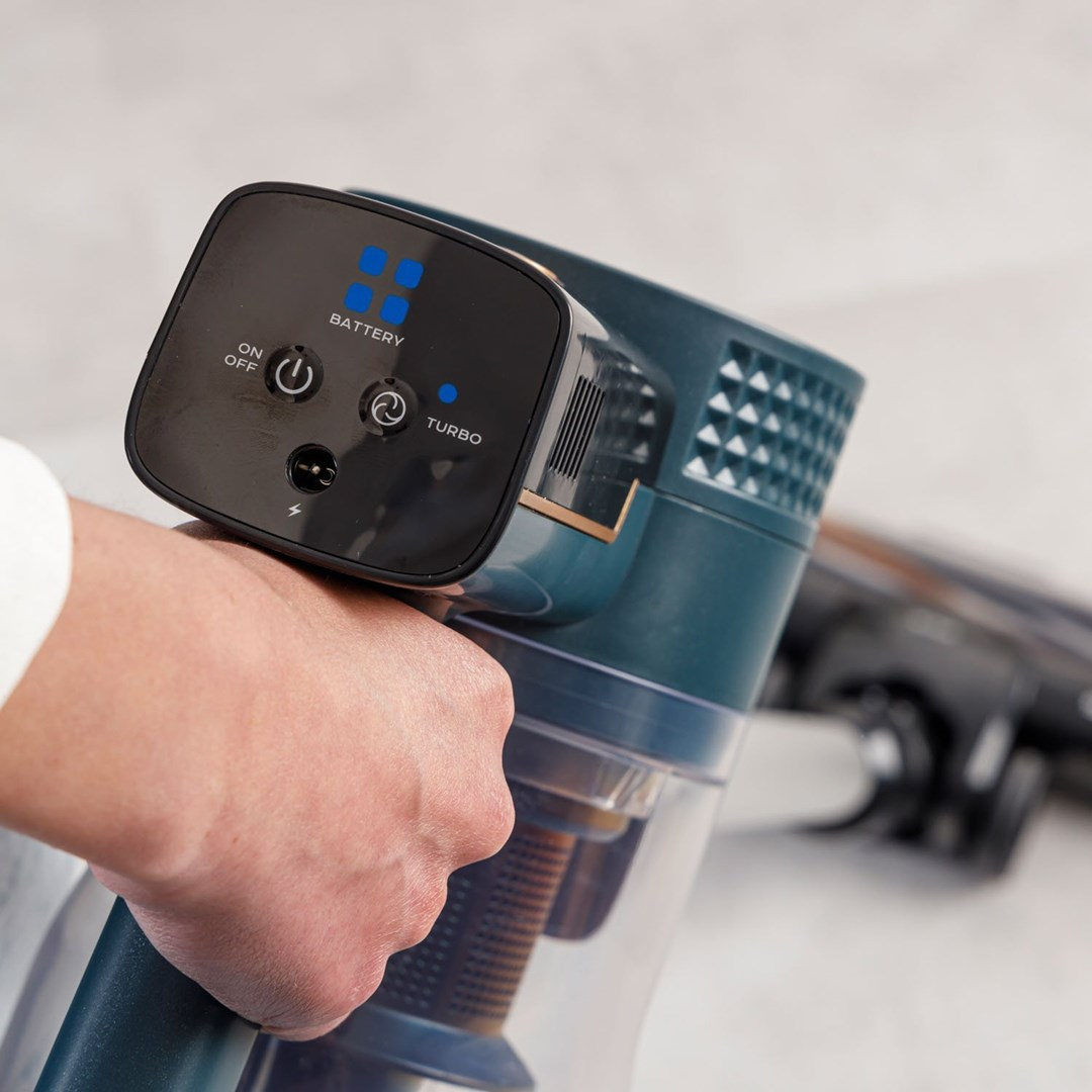Dłoń trzymająca turkusowo-czarny odkurzacz bezprzewodowy. Panel sterowania pokazuje baterię, włącznik/wyłącznik i ustawienia turbo.