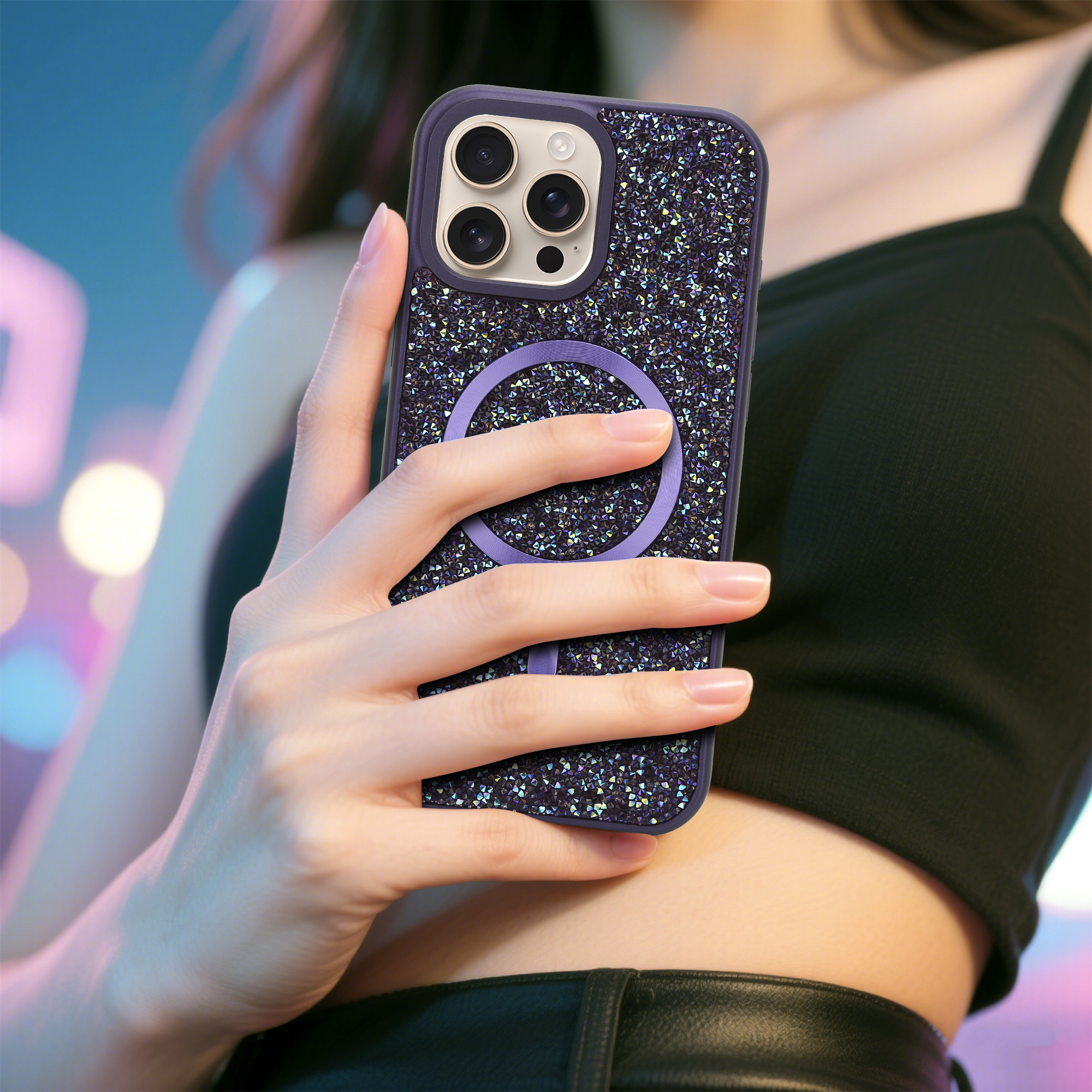 Eine Hand hält ein Handy mit einer glitzernden Hülle. Der Hintergrund ist mit Blau- und Rosatönen unscharf.