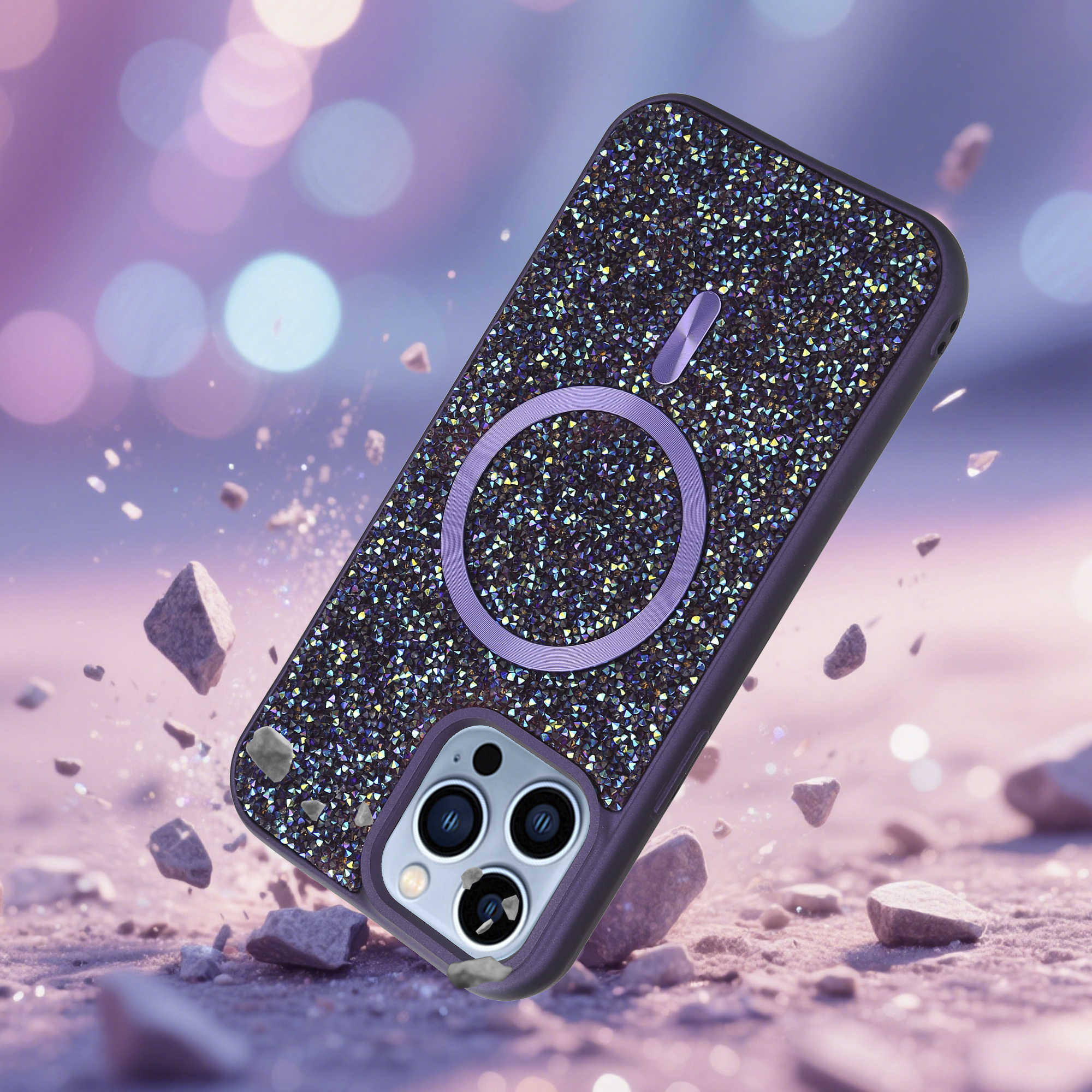 Ein mit Strass besetztes Telefoncase fällt auf eine Oberfläche mit kleinen Steinen. Bokeh-Hintergrund.