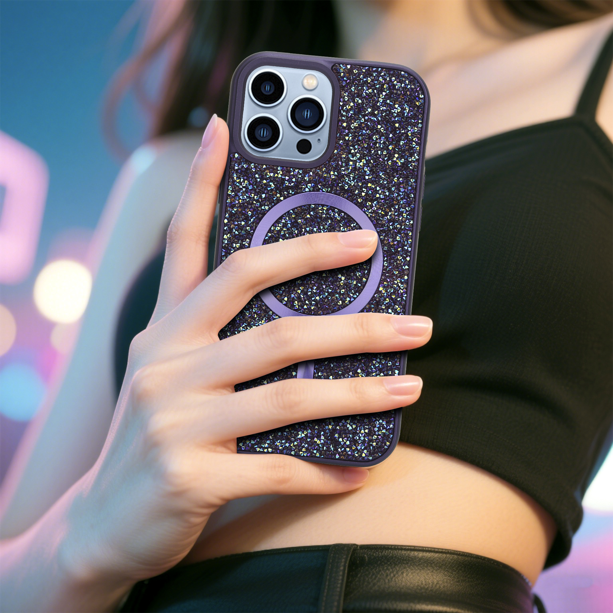 Eine Person hält ein Telefon mit einer glitzernden Hülle. Die Hülle hat einen lila Ring. Der Hintergrund ist verschwommen.