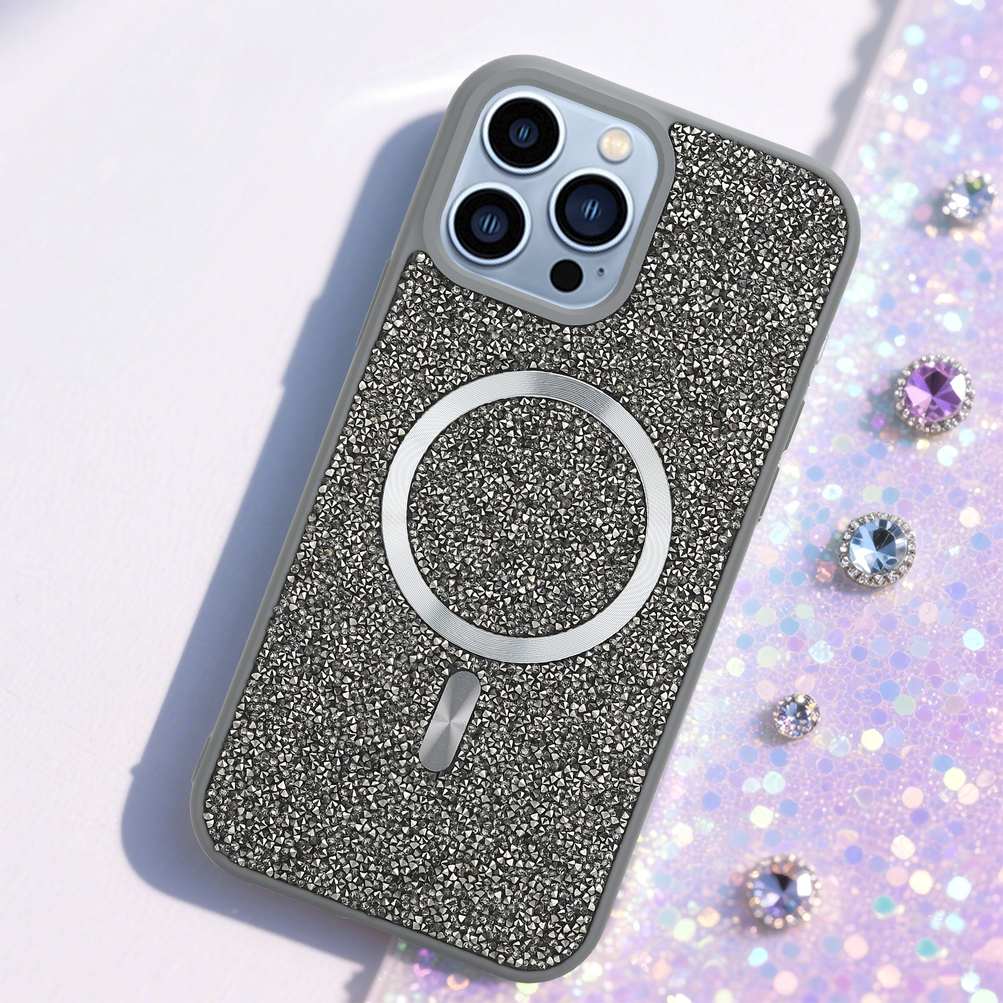 Eine mit Strasssteinen bedeckte iPhone-Hülle. Der Hintergrund hat glitzernden Glitzer und Juwelen.