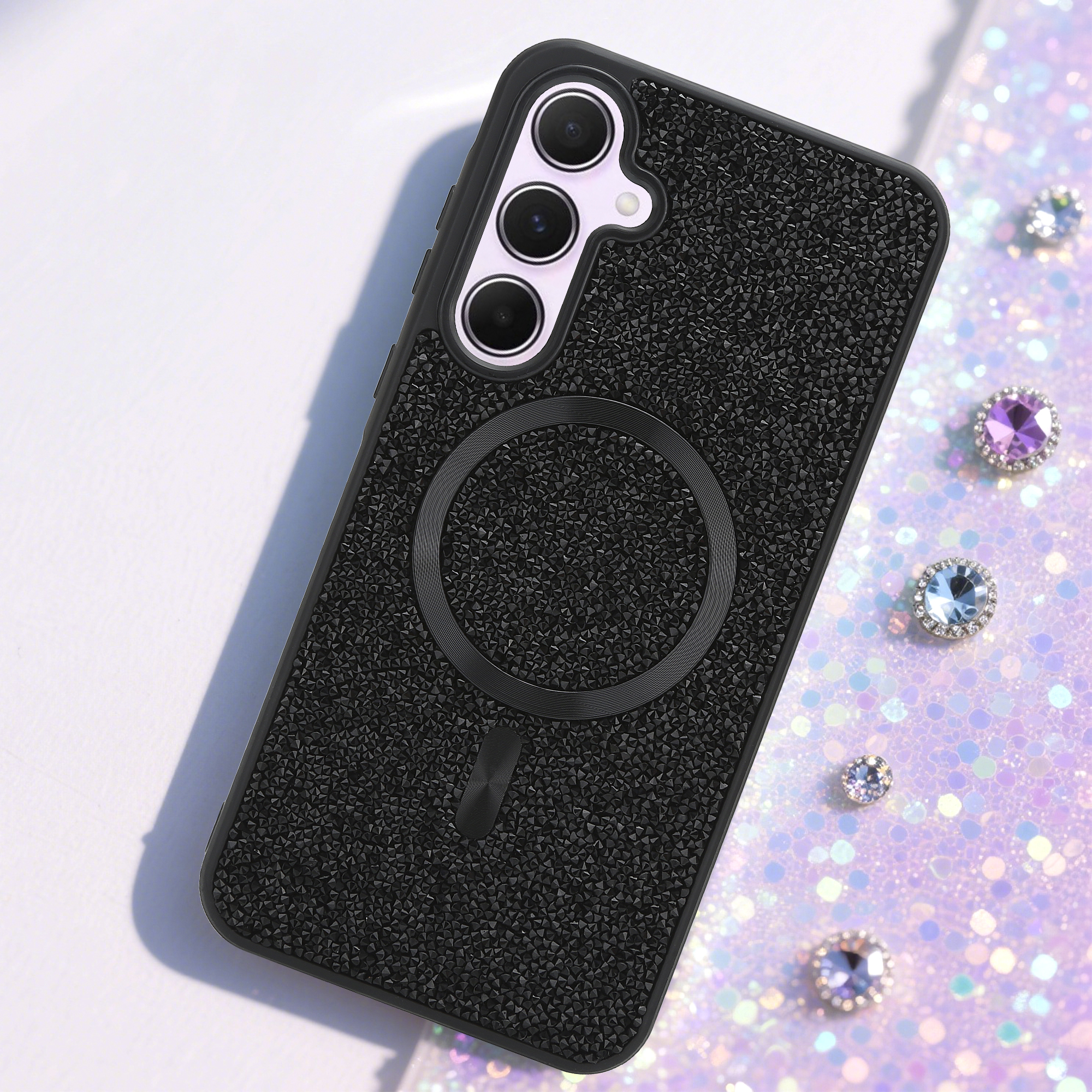 Schwarze Handyhülle mit Kameradetail. Glitzernder Hintergrund mit Edelsteinen.