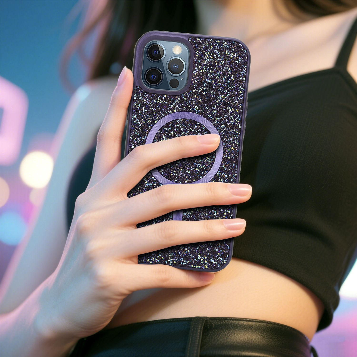 Eine Person hält eine mit Strass besetzte Handyhülle. Das Telefon hat einen lila kreisförmigen Halter. Die Person trägt ein schwarzes Oberteil.