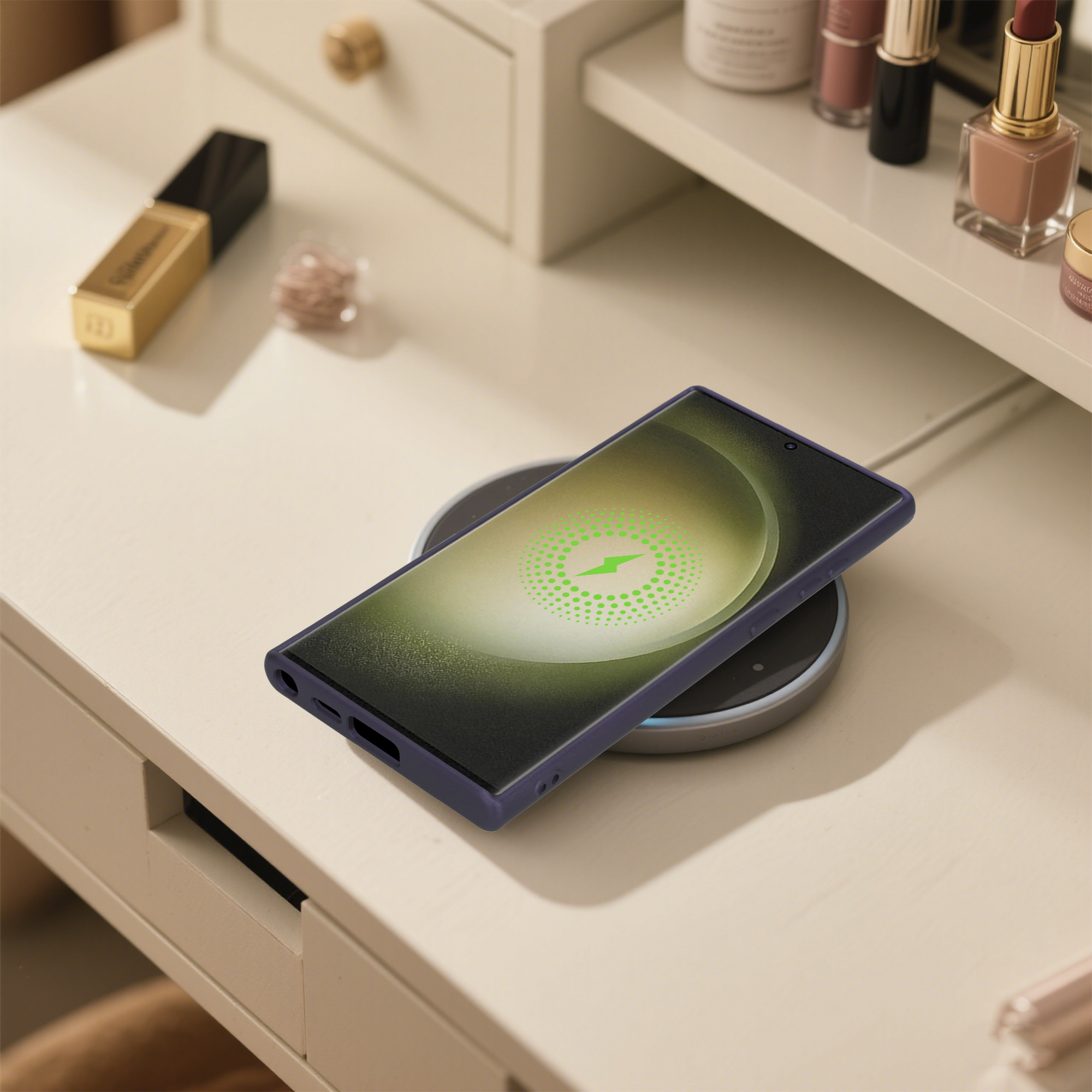 Ein Telefon in einer lila Hülle lädt kabellos auf einem Pad. Make-up-Artikel befinden sich im Hintergrund auf einem weißen Tisch.