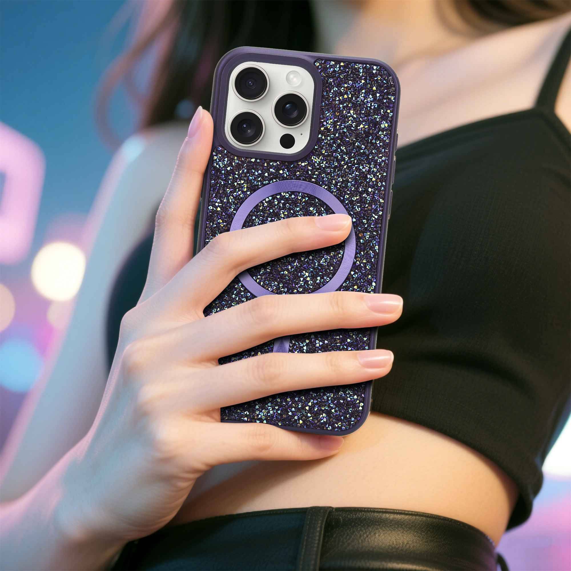 Eine Hand hält eine mit Strass besetzte Handyhülle. Das Telefon hat einen lila Ring. Der Hintergrund ist mit Neonlichtern verschwommen.