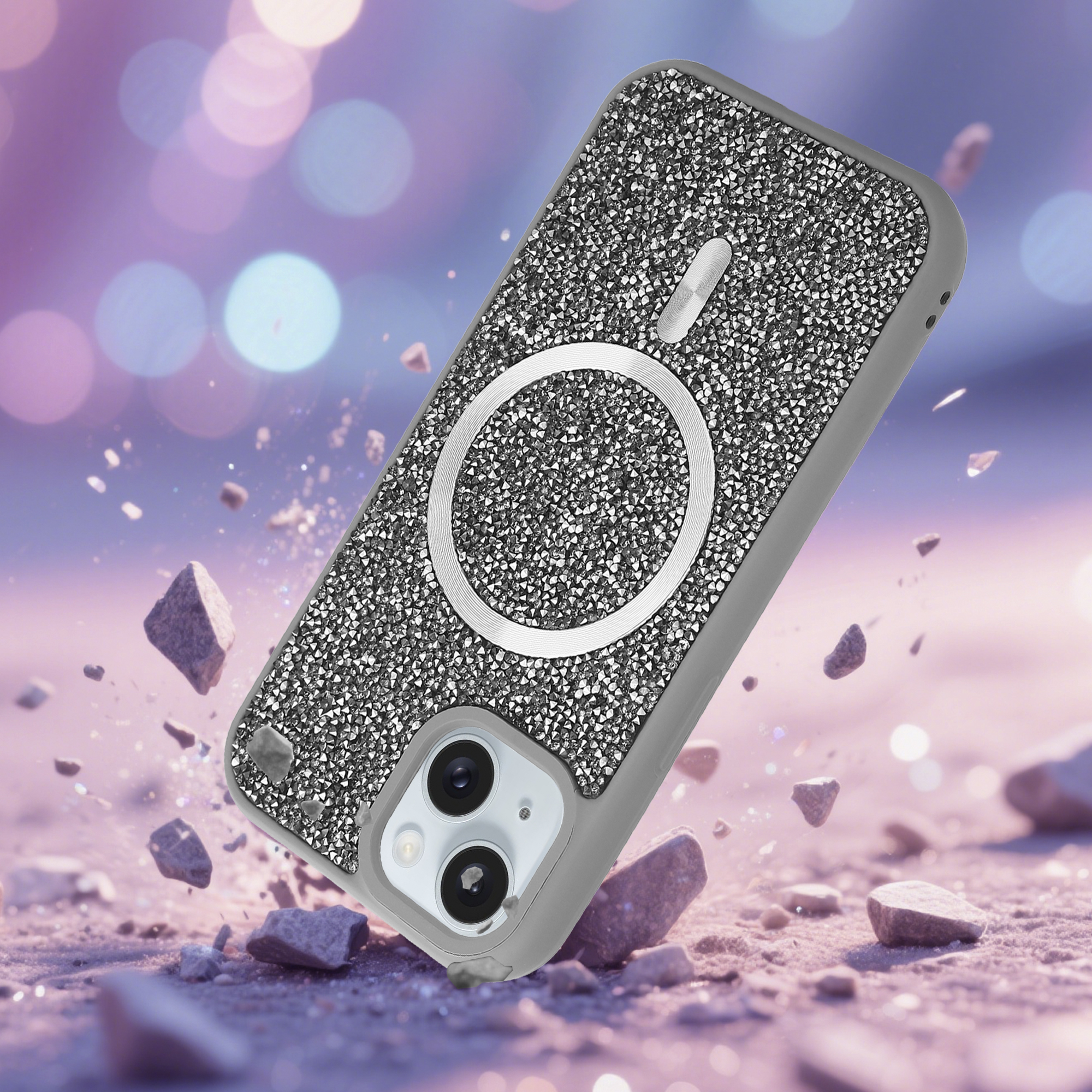 Ein mit Strass besetztes Handycase mit Silberring, das mit Trümmern auf einer rosa Oberfläche mit Bokeh-Lichtern im Hintergrund fällt.