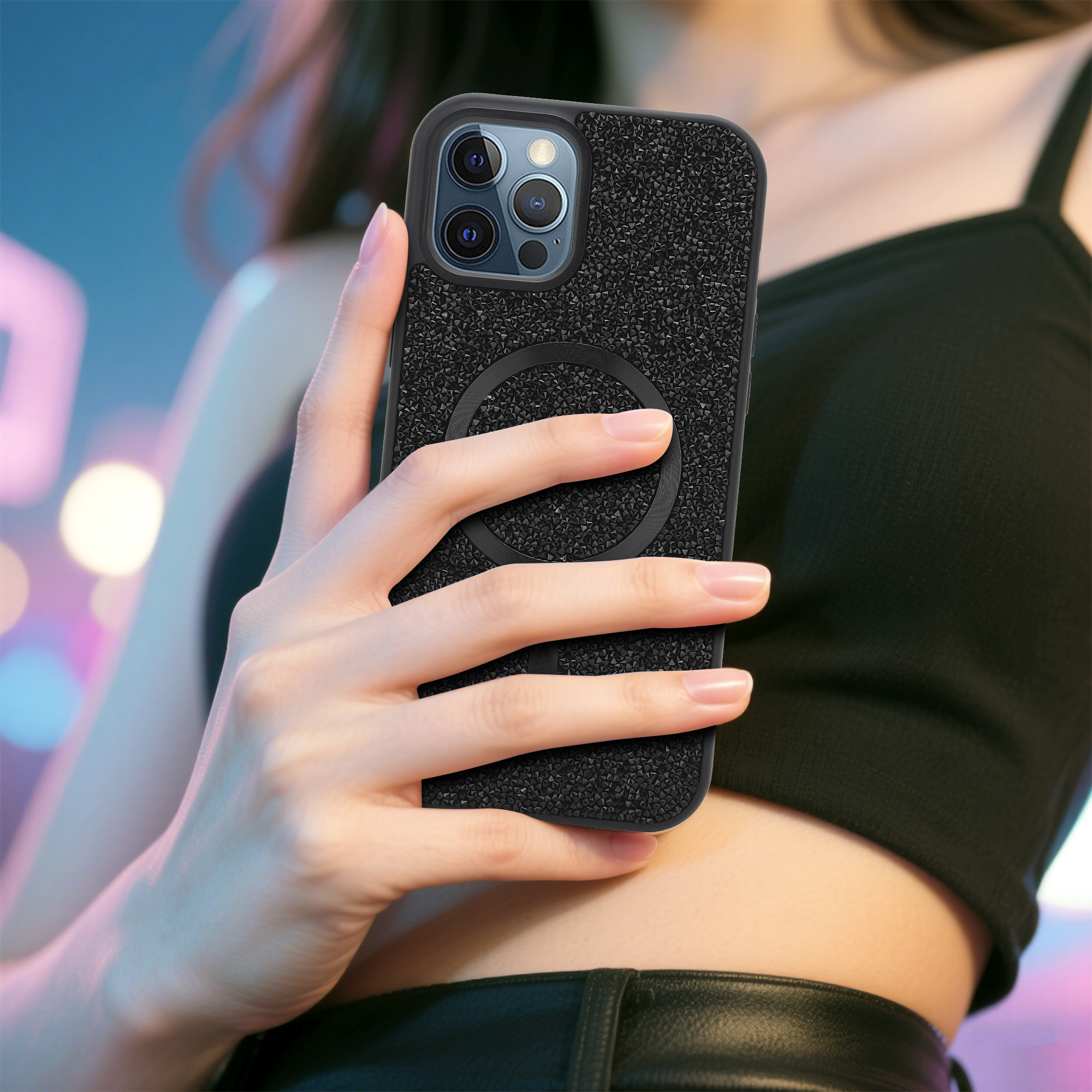 Eine Person hält ein schwarzes Telefon mit strukturierter Hülle. Das Telefon hat einen schwarzen Magnetring auf der Rückseite.