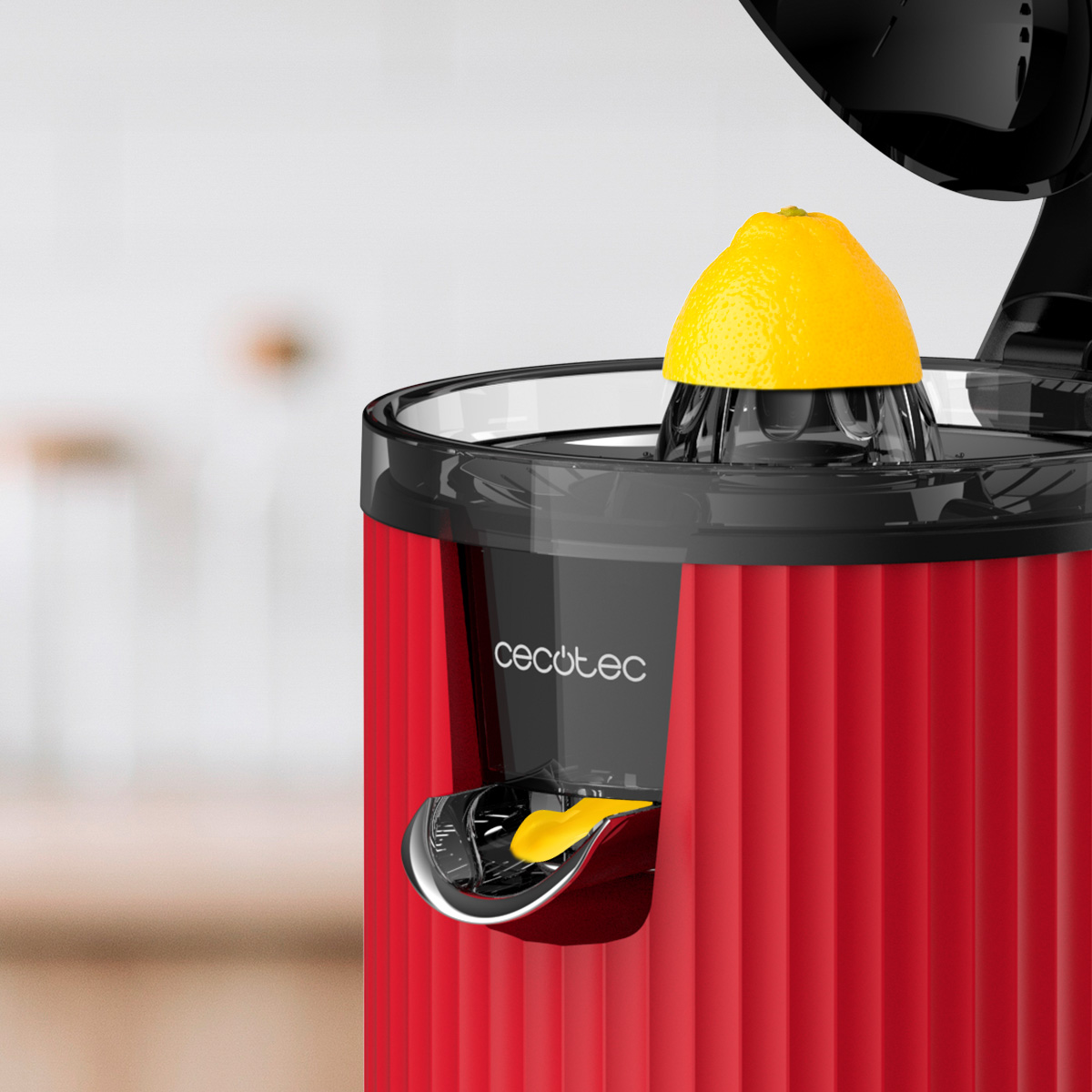Uno spremiagrumi rosso e nero con una metà di limone sopra. Lo spremiagrumi ha un beccuccio. Lo sfondo è sfocato.