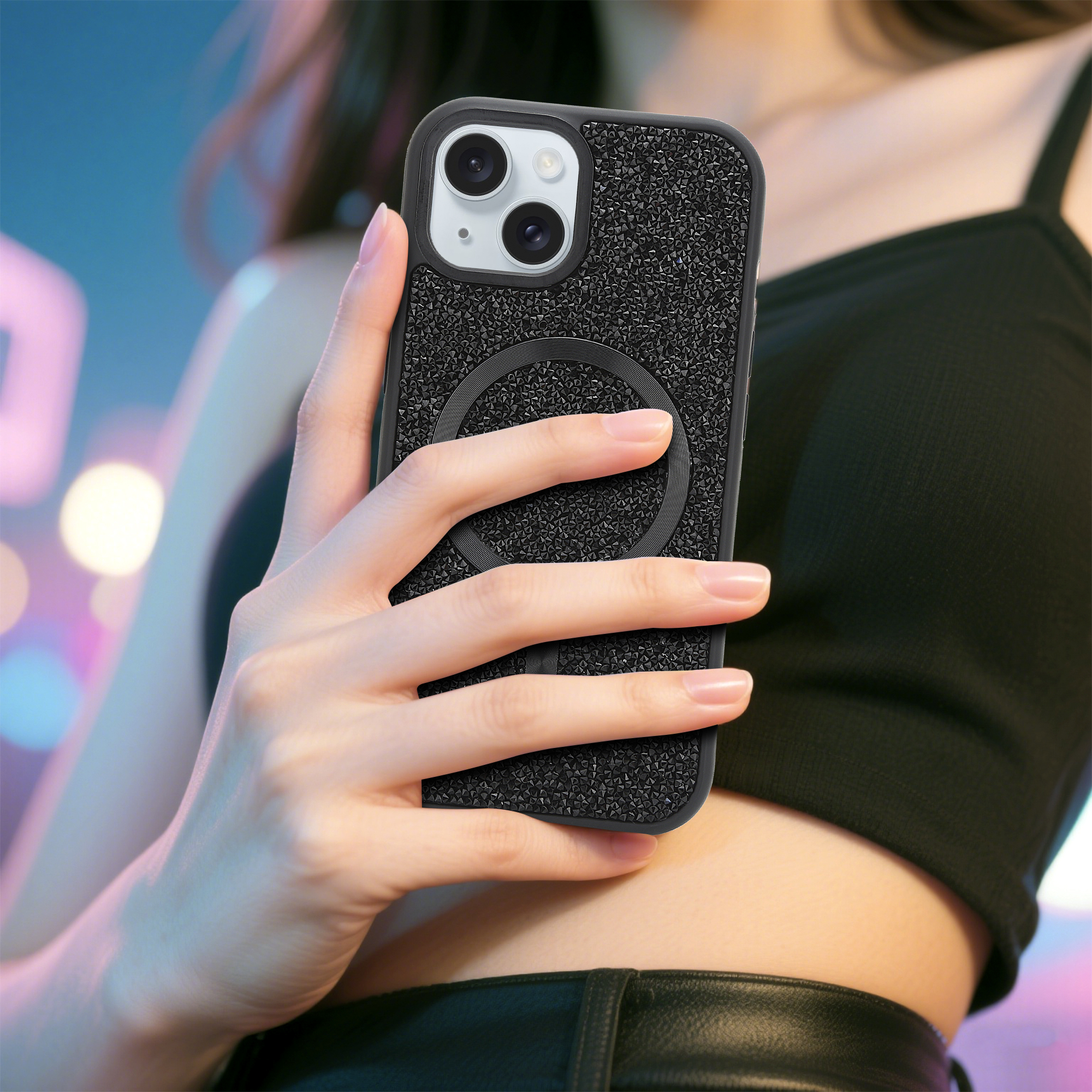 Eine Person hält eine schwarz glitzernde Handyhülle. Die Hülle befindet sich auf einem Telefon mit drei Kameras. Die Person trägt ein schwarzes Oberteil.