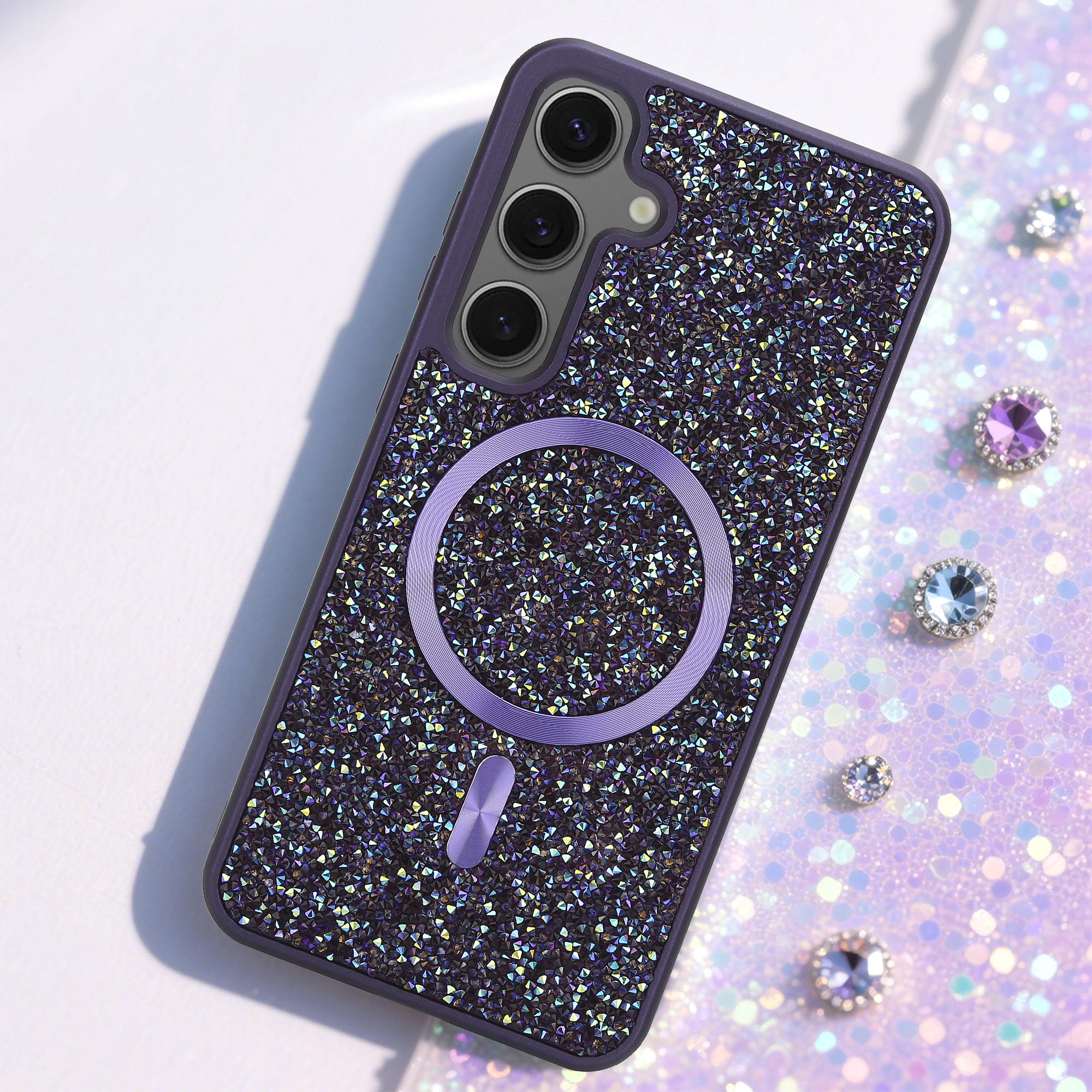Eine mit Strass besetzte Handyhülle mit lila Rahmen und Ring. Der Hintergrund hat Glitzer und Edelsteine.