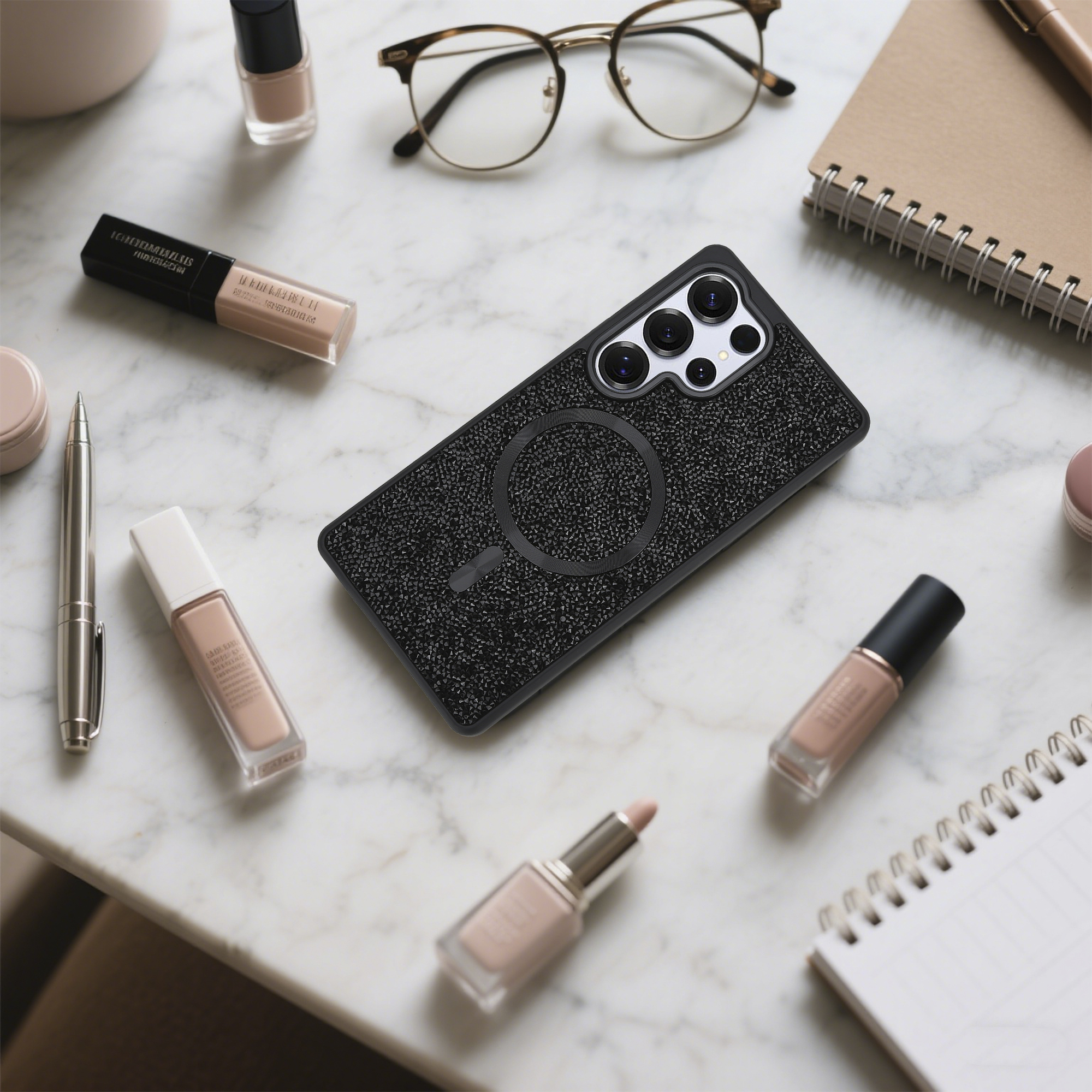 Eine Handyhülle und Make-up-Artikel liegen auf einer Marmoroberfläche. Brille, Notizblock, Stift und Nagellack sind ebenfalls vorhanden.