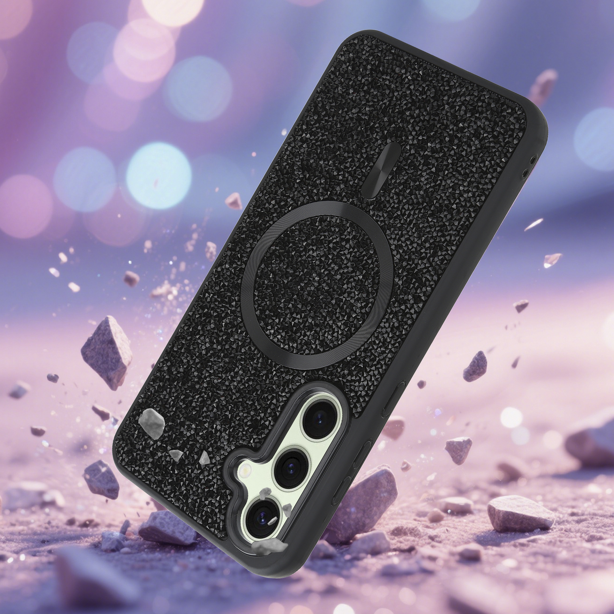Schwarze Handyhülle mit Kristalldesign auf rosa Oberfläche mit Gesteinsfragmenten, Bokeh-Hintergrund.