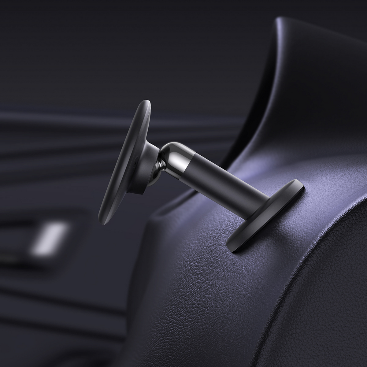 Een close-up van een zwarte telefoonhouder voor in de auto, gemonteerd op een donker dashboard. De houder heeft een ronde basis en een zwenkarm.